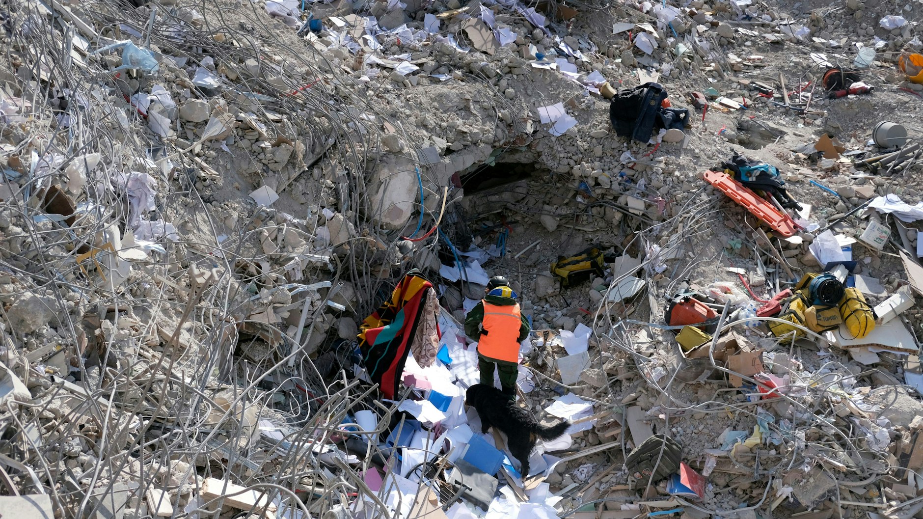 Ein Mann läuft mit seinem Hund durch die Schuttberge von Antakya. 