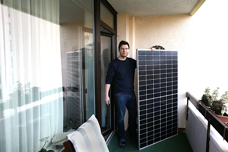 Vjaceslav Hübner (38) mit dem Solarpanel auf seinem Wohnungsbalkon.