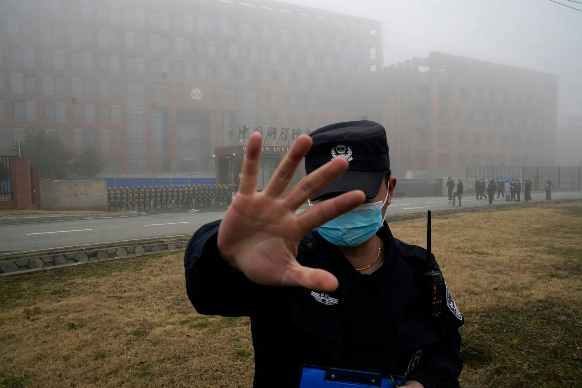 ARCHIV - Ein Security-Mitarbeiter versucht im Februar 2021 vor dem Institut für Virologie in Wuhan, Journalisten am Fotografieren zu hindern. China hat die Hypothese stets zurückgewiesen, dass das Coronavirus aus dem Labor entwichen sein könnte.  
