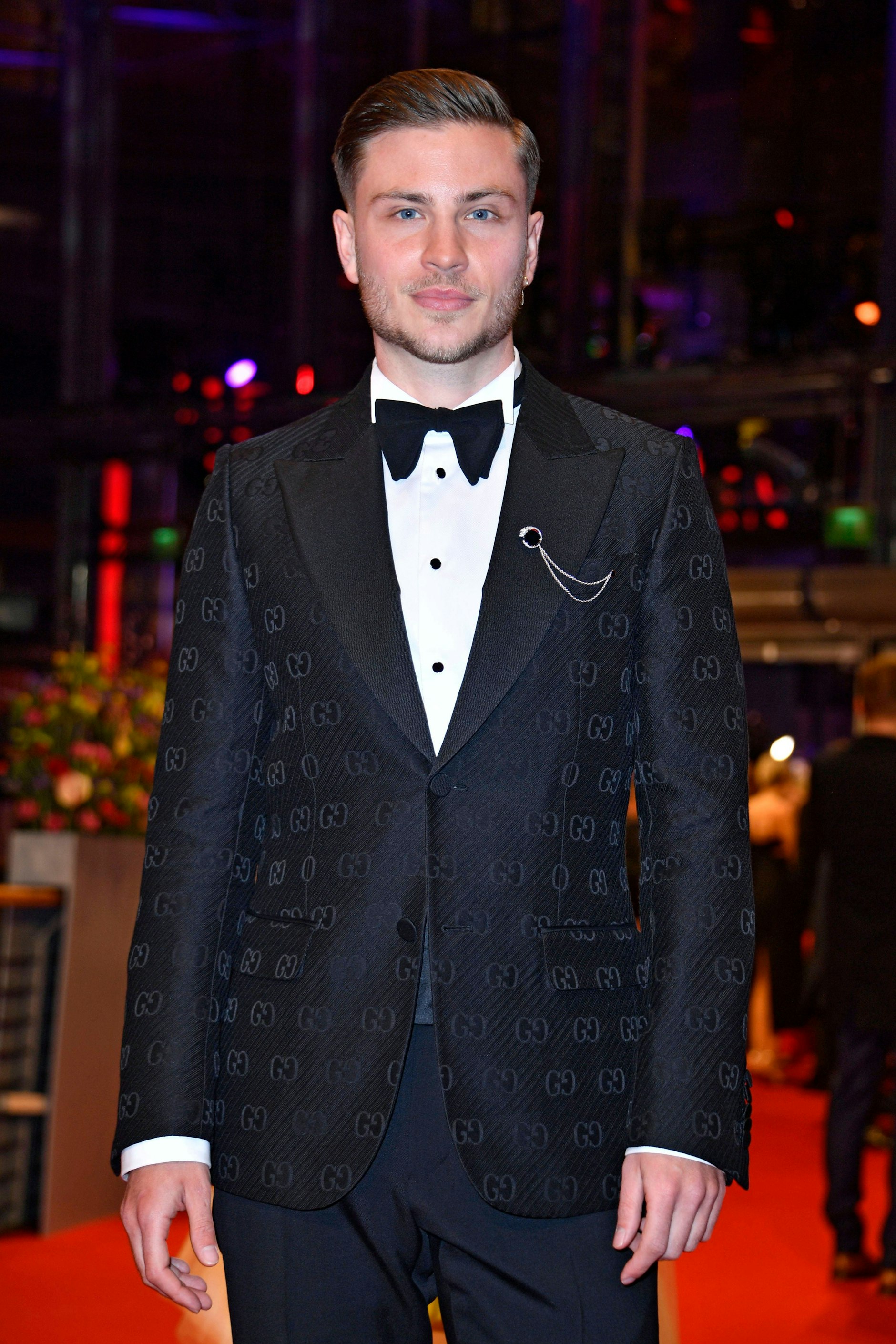 <strong>TOP:</strong> Großformatige Logos und Schriftzüge haben auf dem roten Teppich eigentlich nichts verloren. Eigentlich! Jannik Schümann zeigt, dass Markenembleme eben doch nicht immer prollig aussehen müssen – die Logo-Gs auf seinem Gucci-Jackett schimmern hübsch dezent im Scheinwerferlicht. Das Schmuckkettchen am Revers hätte es da eigentlich gar nicht mehr gebraucht. Und trotzdem: ein wirklich guter Look.