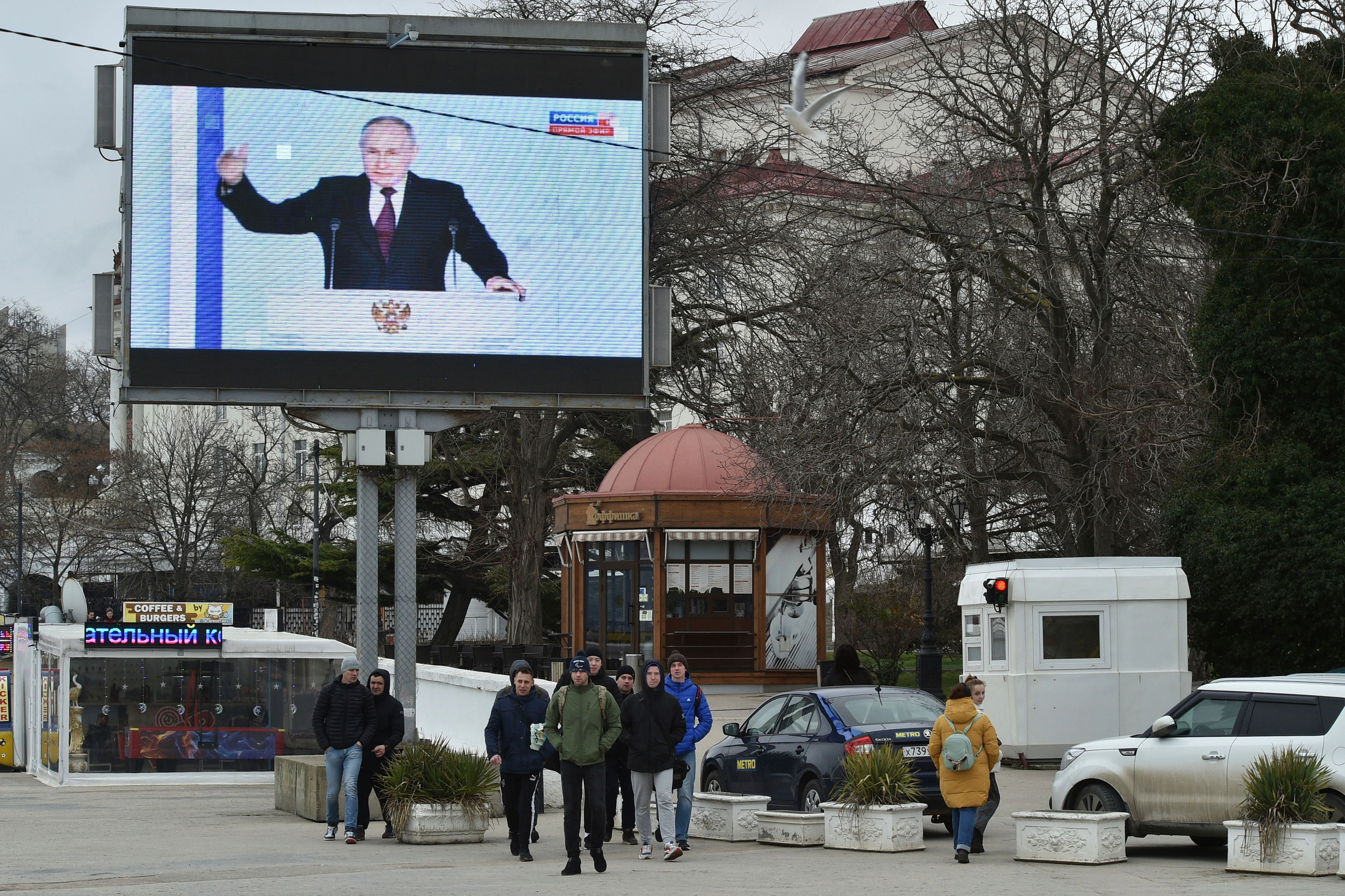Menschen vor einem Fernsehbildschirm, der den russischen Präsidenten Putin während seiner jährlichen Rede zur Lage der Nation in Sewastopol auf der Krim zeigt.