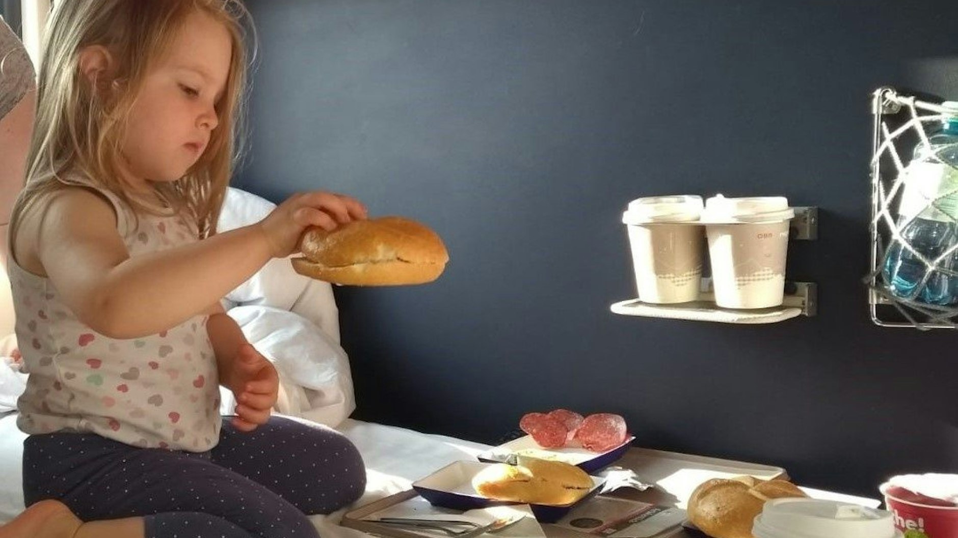 Ein Mädchen sitzt im Nachtzug und frühstückt.