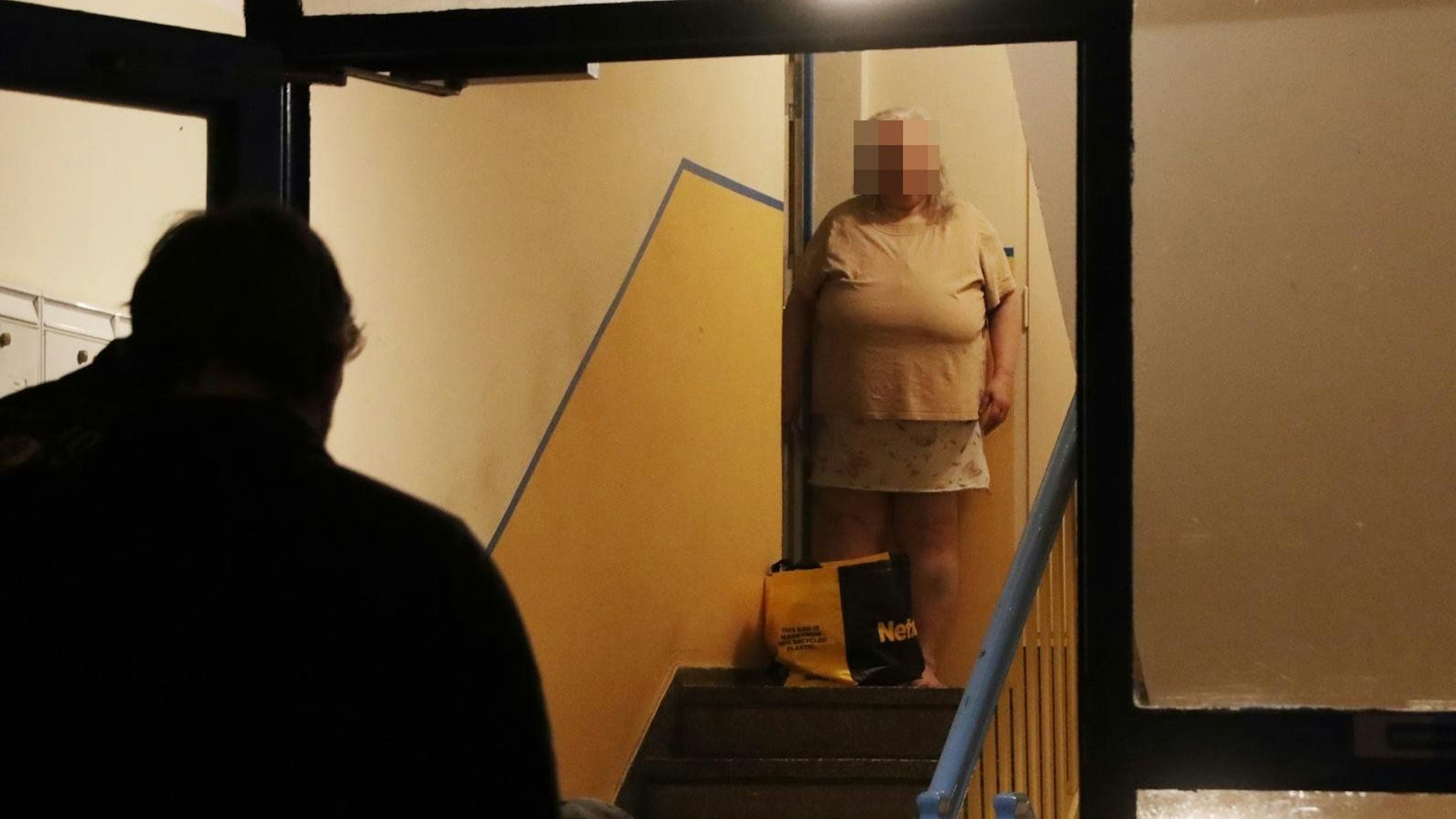 Die offenkundig überforderte Zustellerin steht an der Wohnungstür.