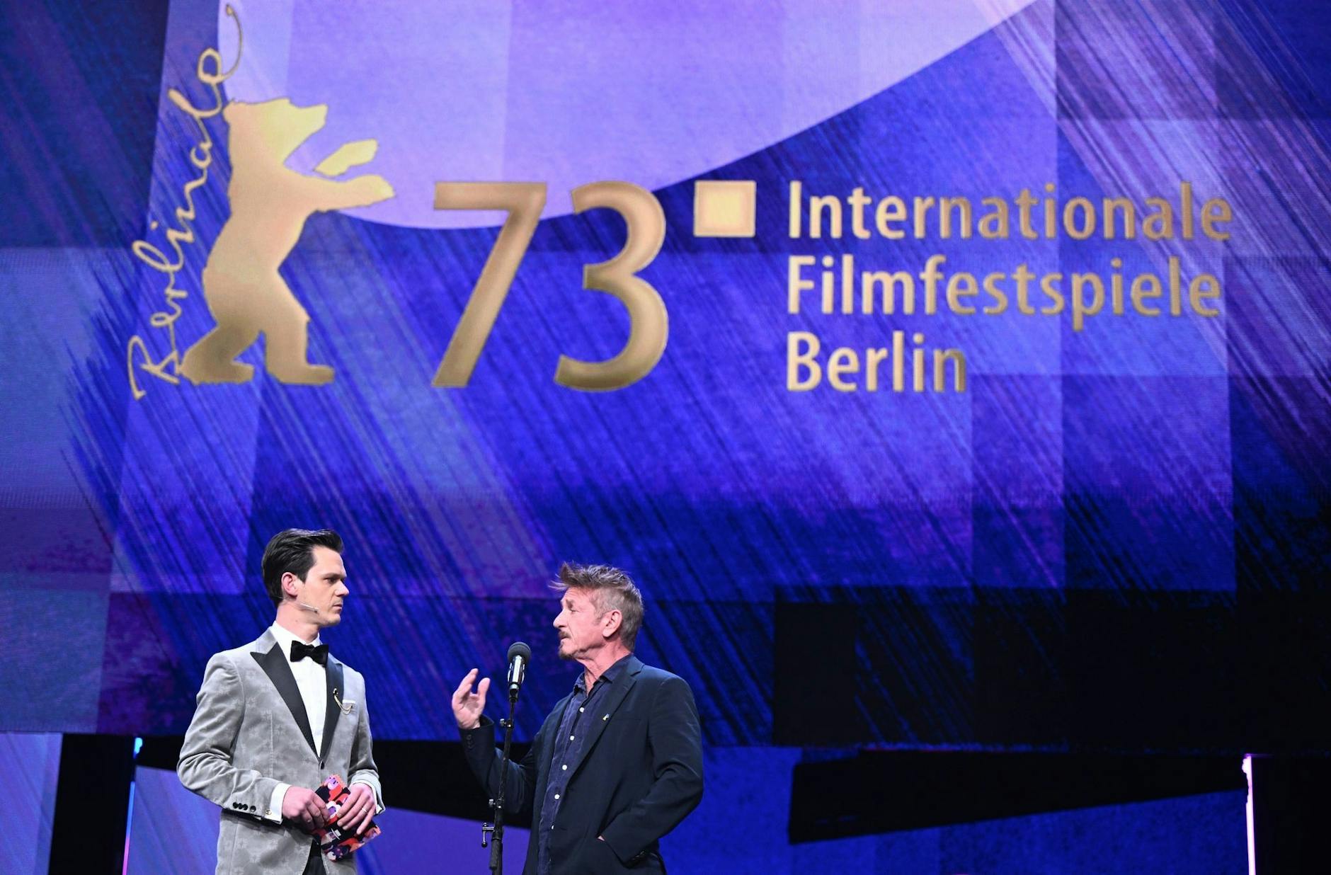 Jo Schück, Moderator der Berlinale Eröffnungsveranstaltung und der Schauspieler und Filmregisseur Sean Penn unterhalten sich auf der Bühne bei der Eröffnung der Berlinale.
