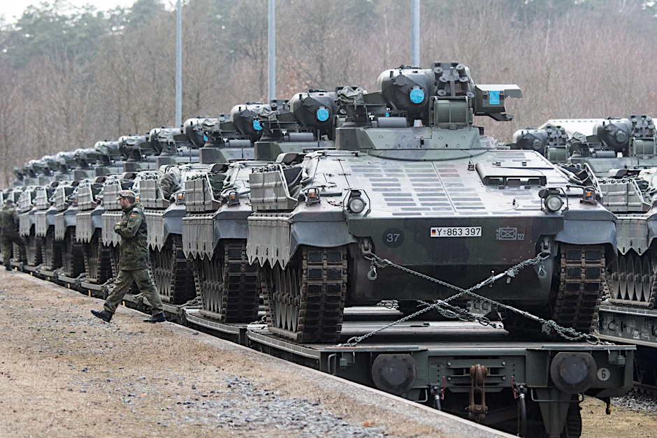 Ein Bundeswehrsoldat vor Schützenpanzern vom Typ Marder, die für den Transport auf einen Zug verladen worden sind.