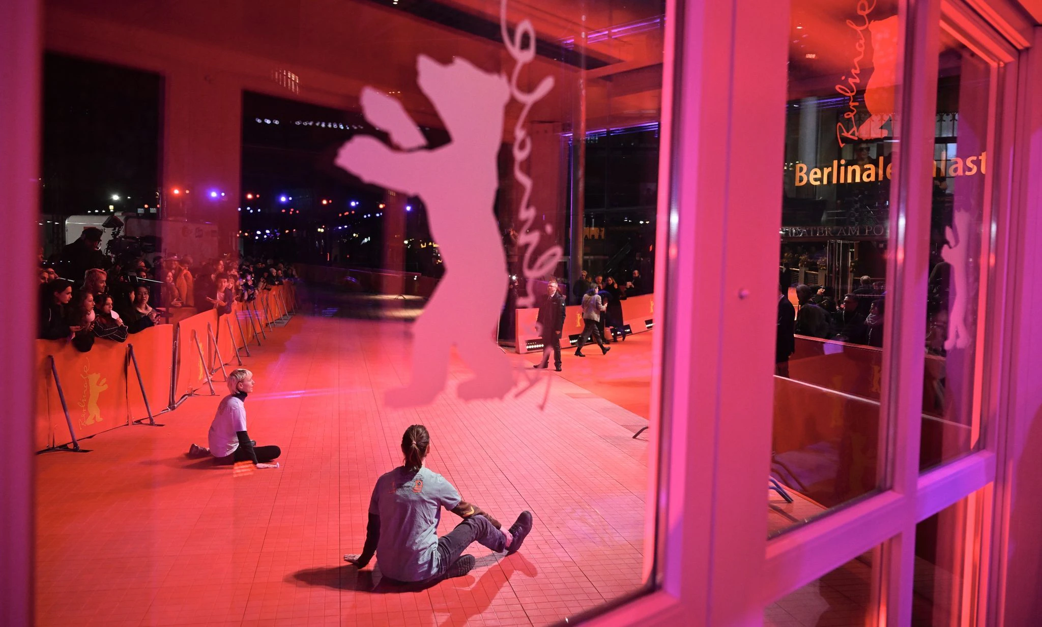 Zwei junge Menschen haben sich auf dem roten Teppich festgeklebt während der Eröffnung der Berlinale.  