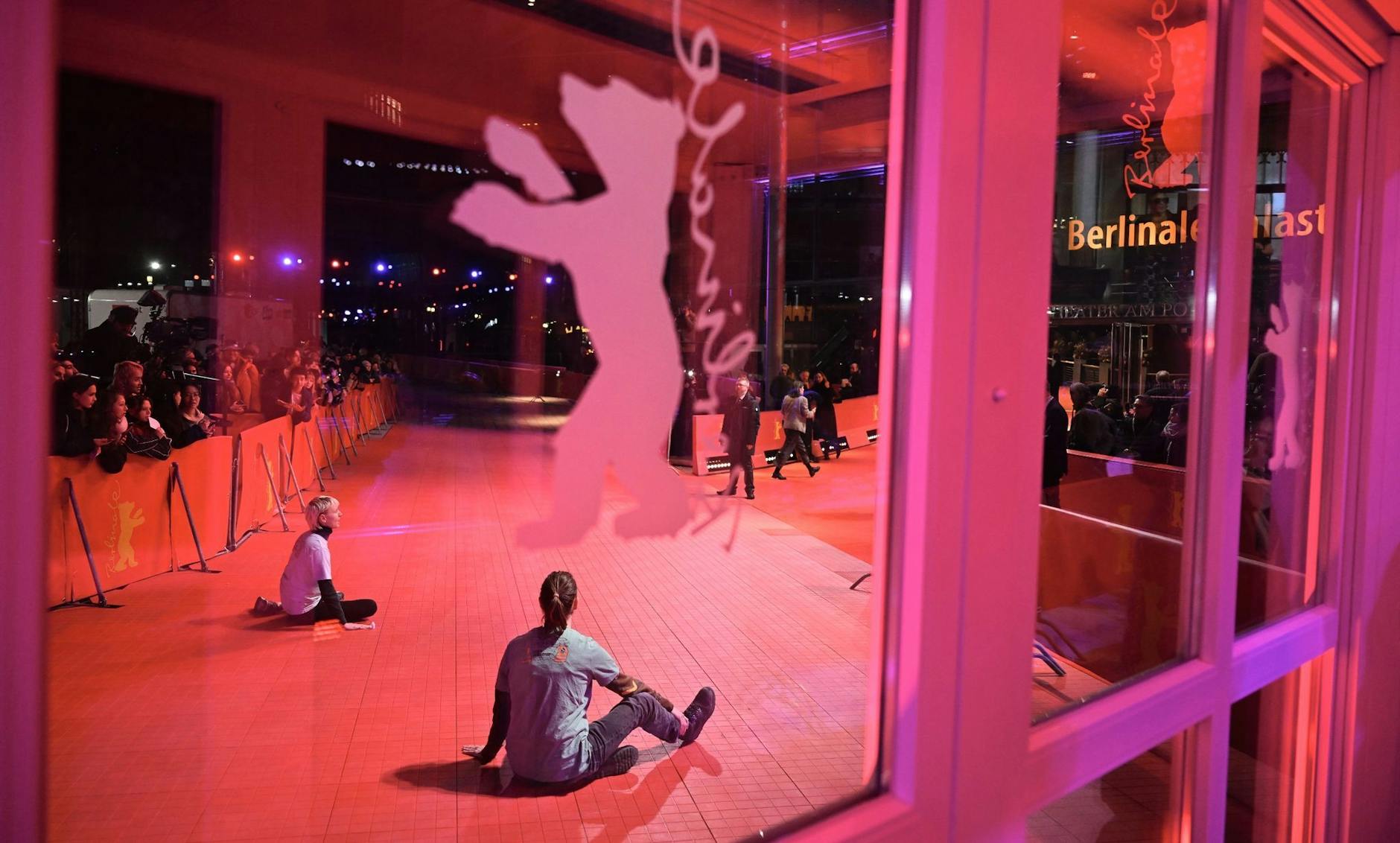 Zwei junge Menschen haben sich auf dem roten Teppich festgeklebt während der Eröffnung der Berlinale.