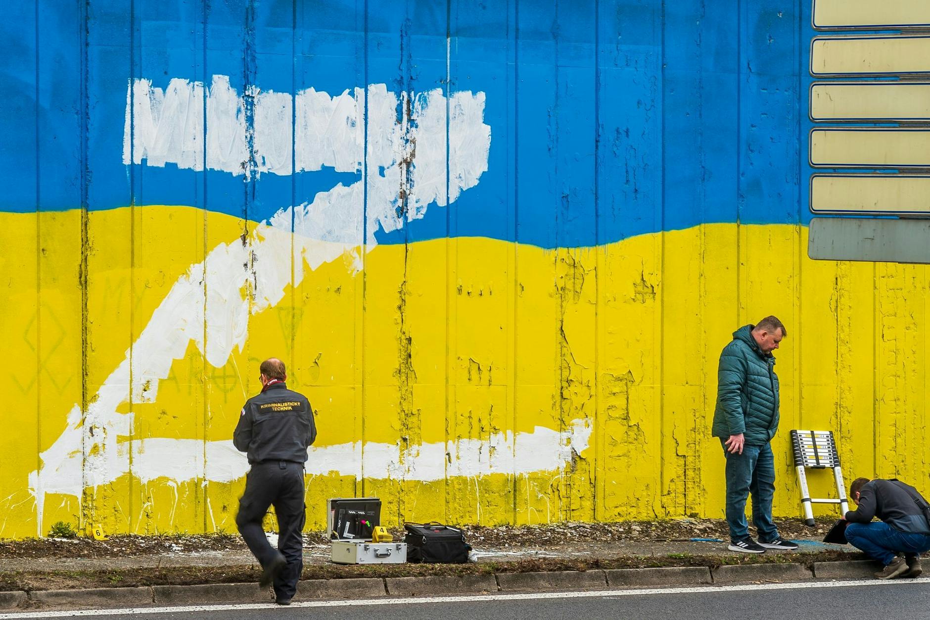 Ermittler stehen vor einer Wand, auf die der Großbuchstabe Z gemalt wurde.
