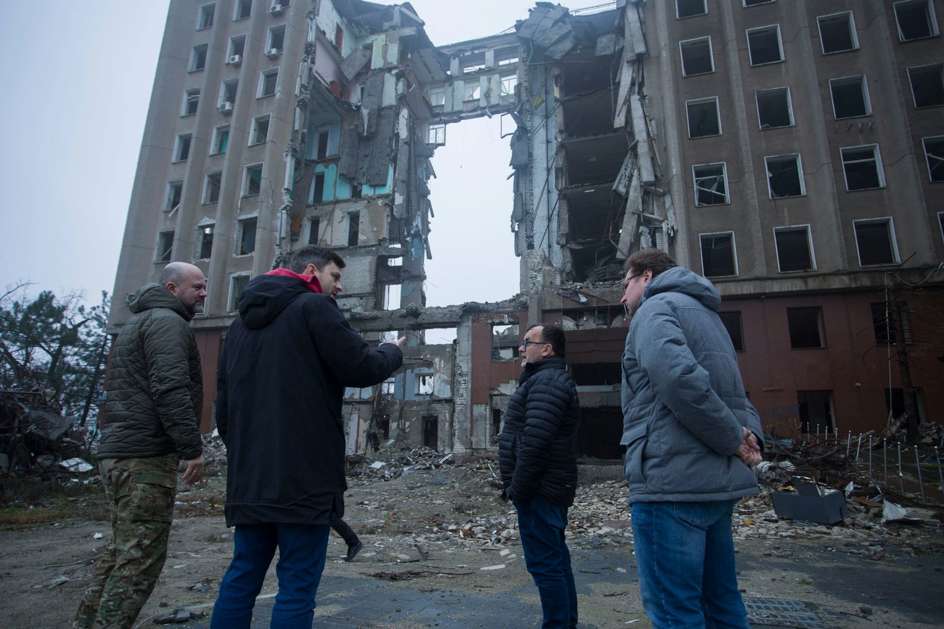 Recherche vor Ort: Pater Patrick Desbois (M.), Andrej Umansky (r.) und Ruslan Kavatsiuk (2.v.l.) vor dem Gebäude der Regionalverwaltung von Mykolajiw, das durch eine „Kalibr“-Rakete am 29. März 2022 zerstört wurde. 37 Menschen kamen dabei ums Leben.&nbsp;