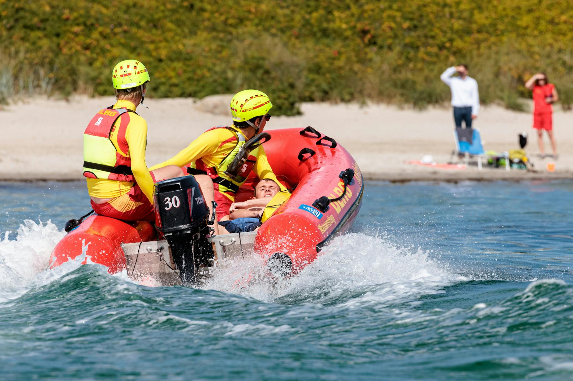 DLRG-Rettungsschwimmer bringen bei einer Übung einen Statisten zurück an den Strand.