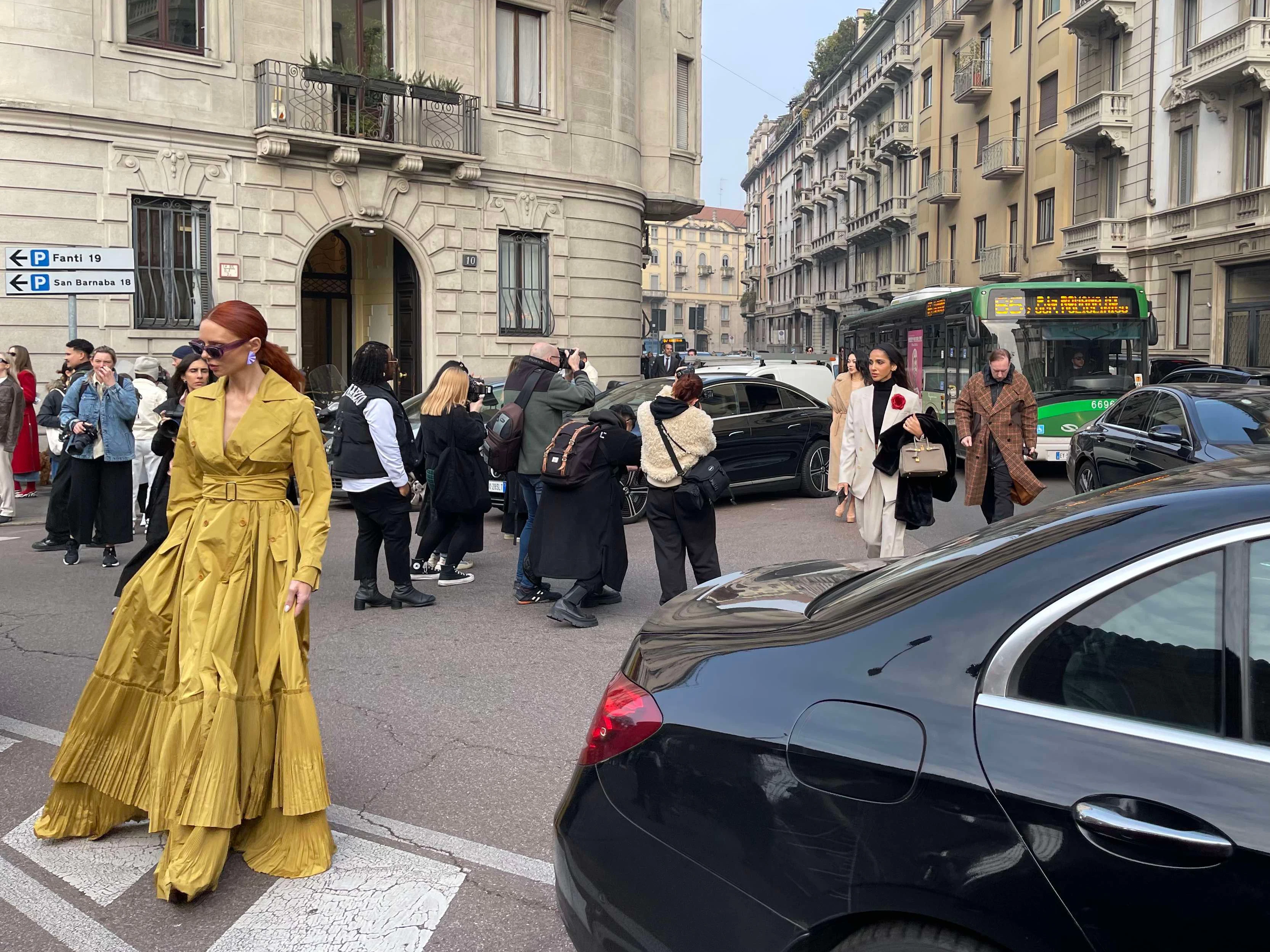 Fotografen und ankommende Gäste verstopfen die Straße. Links in senfgelber Üppigkeit: Instagrammerin Evelyn Kazantzoglou.