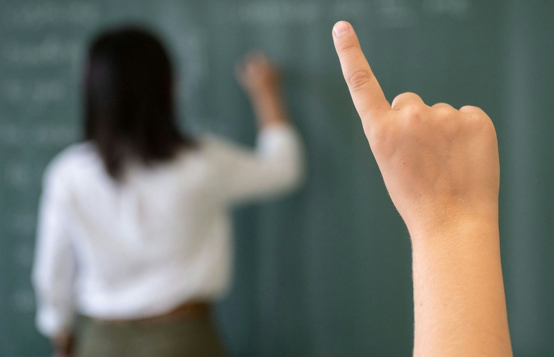 ARCHIV - Ein Schüler meldet sich, während die Lehrerin an die Tafel schreibt.  