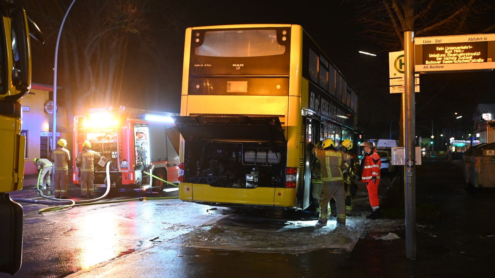 Einsatzkräfte der Feuerwehr inspizieren den verkohlten Bus.