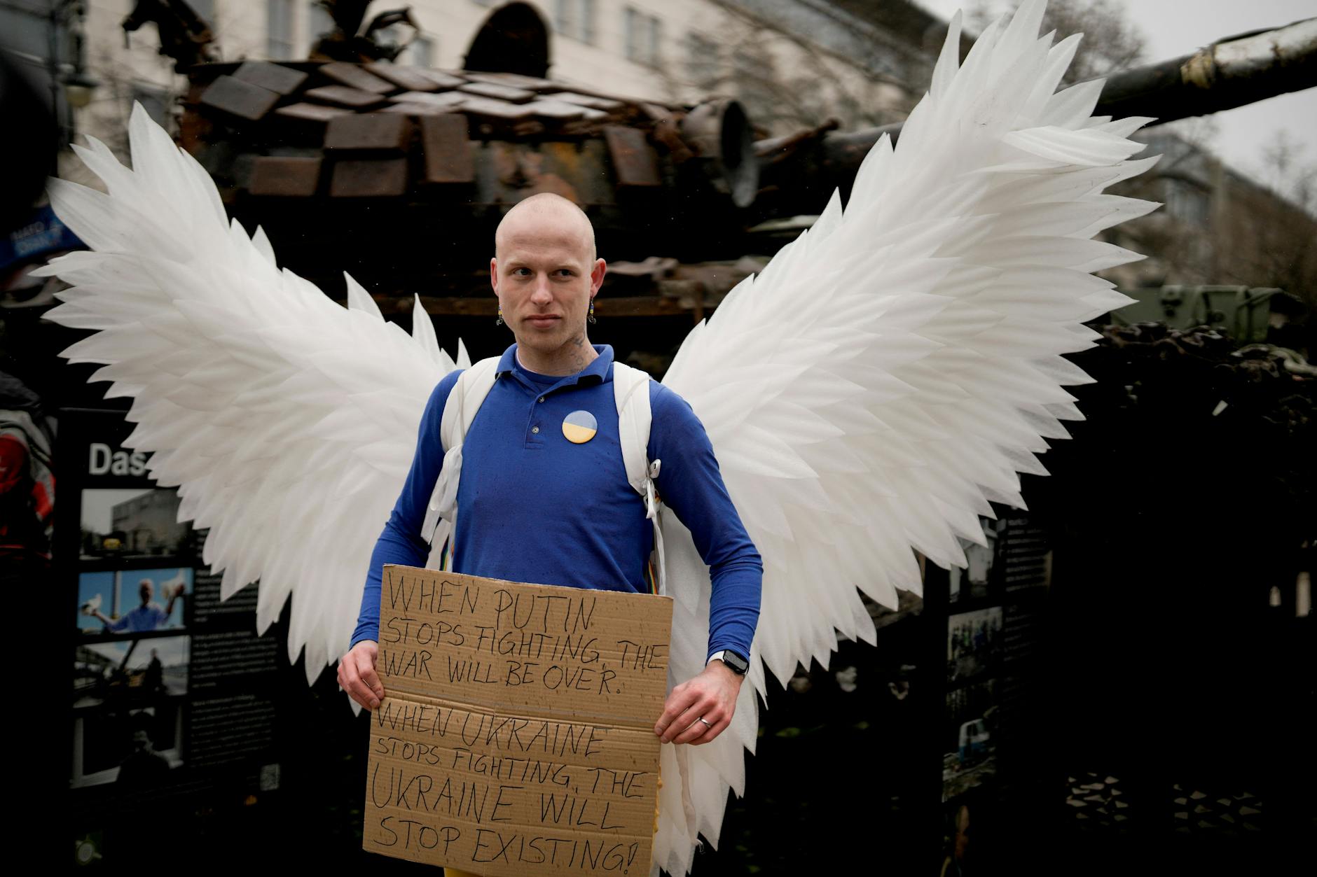 Ein Mann mit den Flügeln einer Friedenstaube vor dem Wrack eines russischen Panzers in Berlin. „Wenn Putin aufhört zu kämpfen, ist der Krieg vorbei“ steht auf dem Schild. „Wenn die Ukraine aufhört zu kämpfen, hört sie auf zu existieren.“