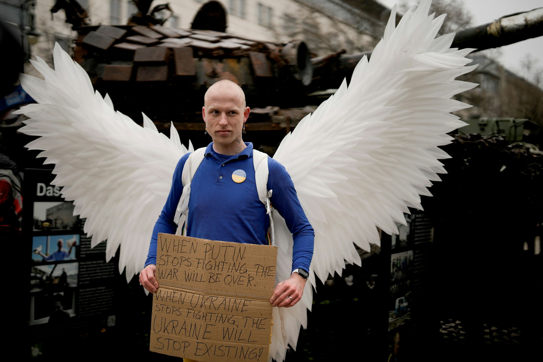 Ein Mann mit den Flügeln einer Friedenstaube vor dem Wrack eines russischen Panzers in Berlin. „Wenn Putin aufhört zu kämpfen, ist der Krieg vorbei“ steht auf dem Schild. „Wenn die Ukraine aufhört zu kämpfen, hört sie auf zu existieren.“