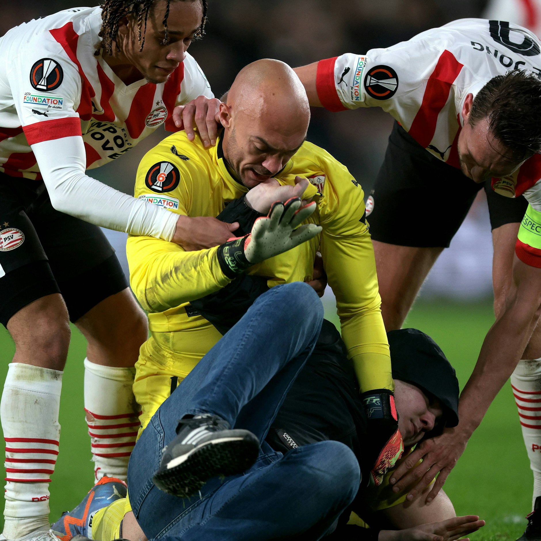 Selbst die Spieler von PSV Eindhoven halfen Sevillas Keeper Marko Dmitrovic dabei, den Gewalttäter dingfest zu machen.