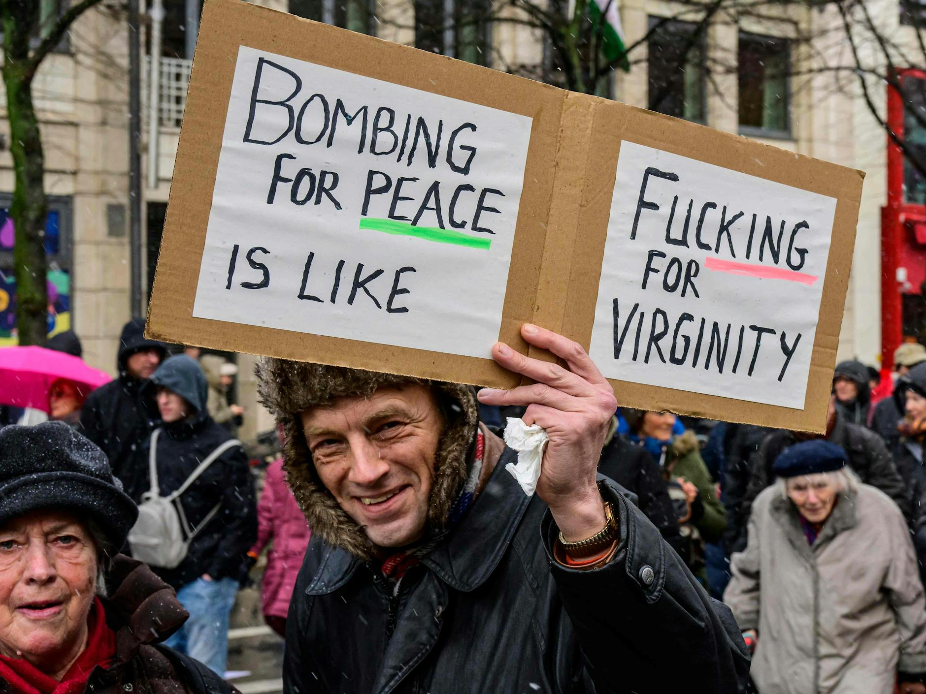 „Bombardierung für den Frieden ist wie fic*** für die Jungfreulichkeit“: Ein Teilnehmer der Kundgebung zeigt stolz sein Schild in die Kamera.