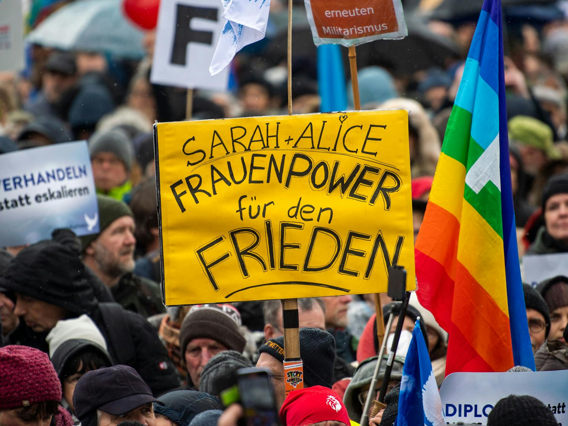 Ein Teilnehmer der Demonstration hält am Brandenburger Tor ein Plakat mit der Aufschrift „Sarah + Alice - Frauenpower für den Frieden“.