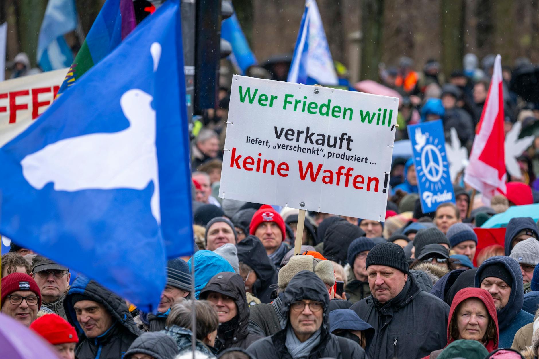 Berlin: Ein Teilnehmer der Demonstration hält ein Schild mit der Aufschrift „Wer Frieden will verkauft, liefert,‚verschenkt‘, produziert keine Waffen“.
