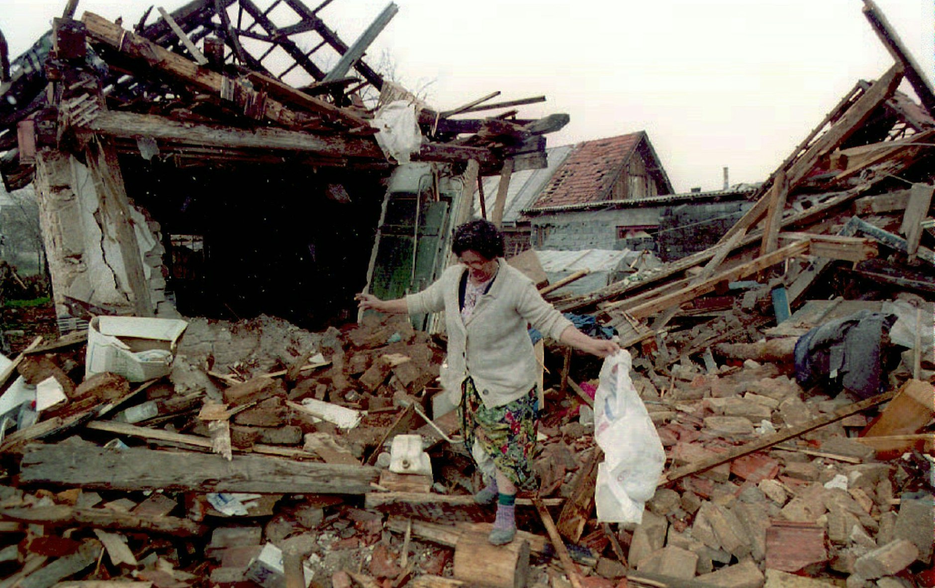 Eine bosnische Frau sucht in den Trümmern ihres zerstörten Wohnhauses nach den letzten Habseligkeiten.