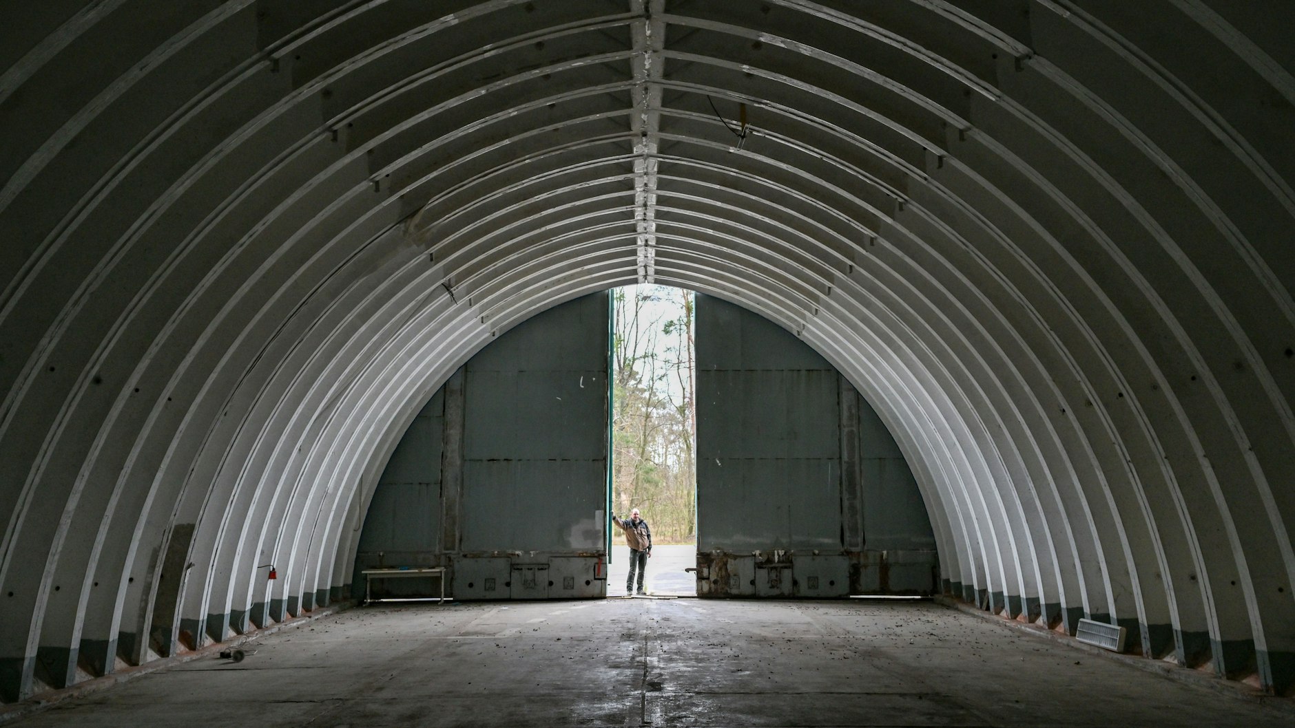Matthias Jahncke, Garten- und Landschaftsbauer, steht am Eingang zu einem alten Flugzeughangar auf dem Flugplatz Neuhardenberg. Er träumt von einer Pension, für die er auch seinen Shelter umbauen will. Außerdem soll sein Büro dort rein.