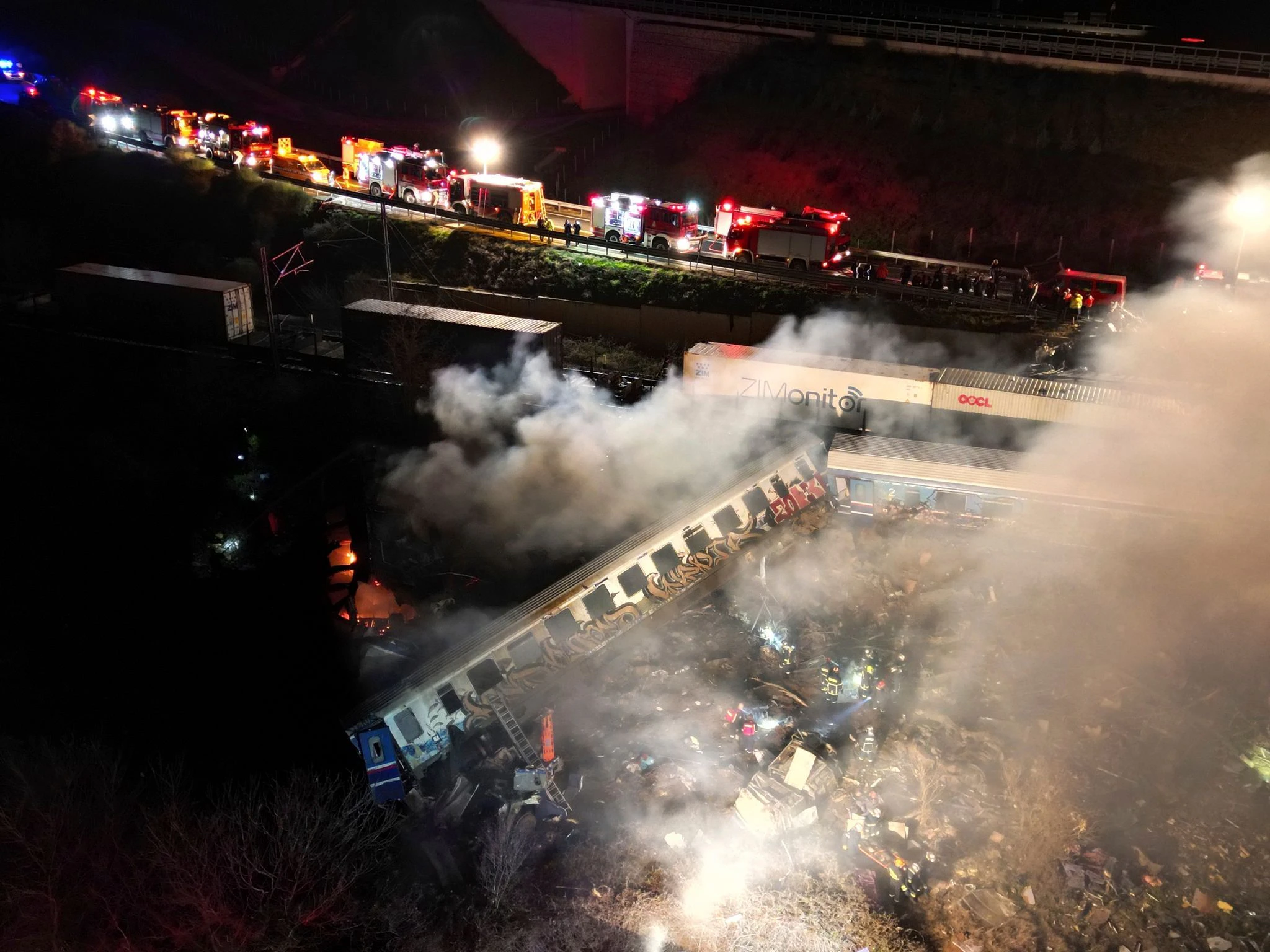 Rauch steigt auf, während Feuerwehrleute und Rettungskräfte nach dem Zusammenstoß der beiden Züge nahe Larissa im Einsatz sind.  