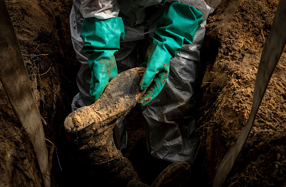Ein Mitarbeiter der Rettungsdienste hält das Bein eines Zivilisten. Die ukrainischen Behörden entdeckten in der Nähe der zurückeroberten Stadt Isjum Hunderte von Gräbern.
