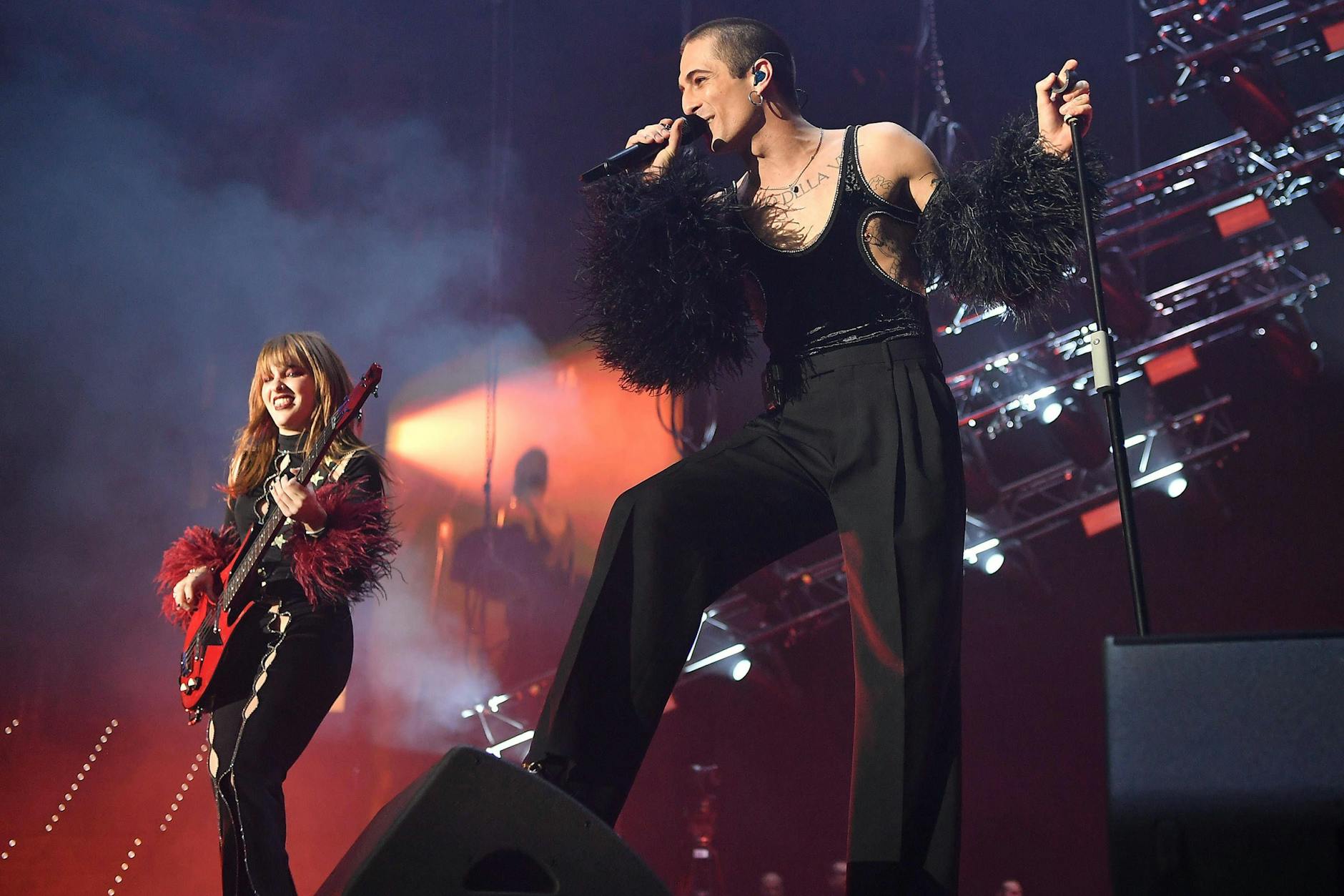 Måneskin beim Konzert, mit Sänger <a href="https://www.google.com/search?rlz=1CAGMMR_enDE886&sxsrf=AJOqlzU5Mu3aBQtqC8f8RCHUIgZOtWR3uw:1678176724292&q=Damiano+David&stick=H4sIAAAAAAAAAONgVuLVT9c3NEwzrioyNMuqfMRowS3w8sc9YSn9SWtOXmPU5OIKzsgvd80rySypFJLmYoOyBKX4uVB18ixi5XVJzM1MzMtXcEksy0wBAOh9wsJcAAAA&sa=X&ved=2ahUKEwi_9pW8r8n9AhX9RvEDHSu6CYgQzIcDKAB6BAgXEAE">Damiano David</a> rechts im Bild