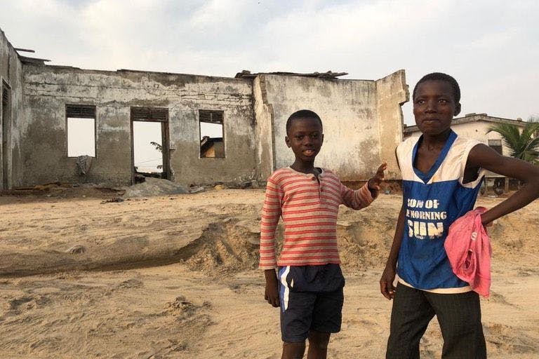 Kinder vor einem zerstörten Haus am Strand in Brenu, Ghana.