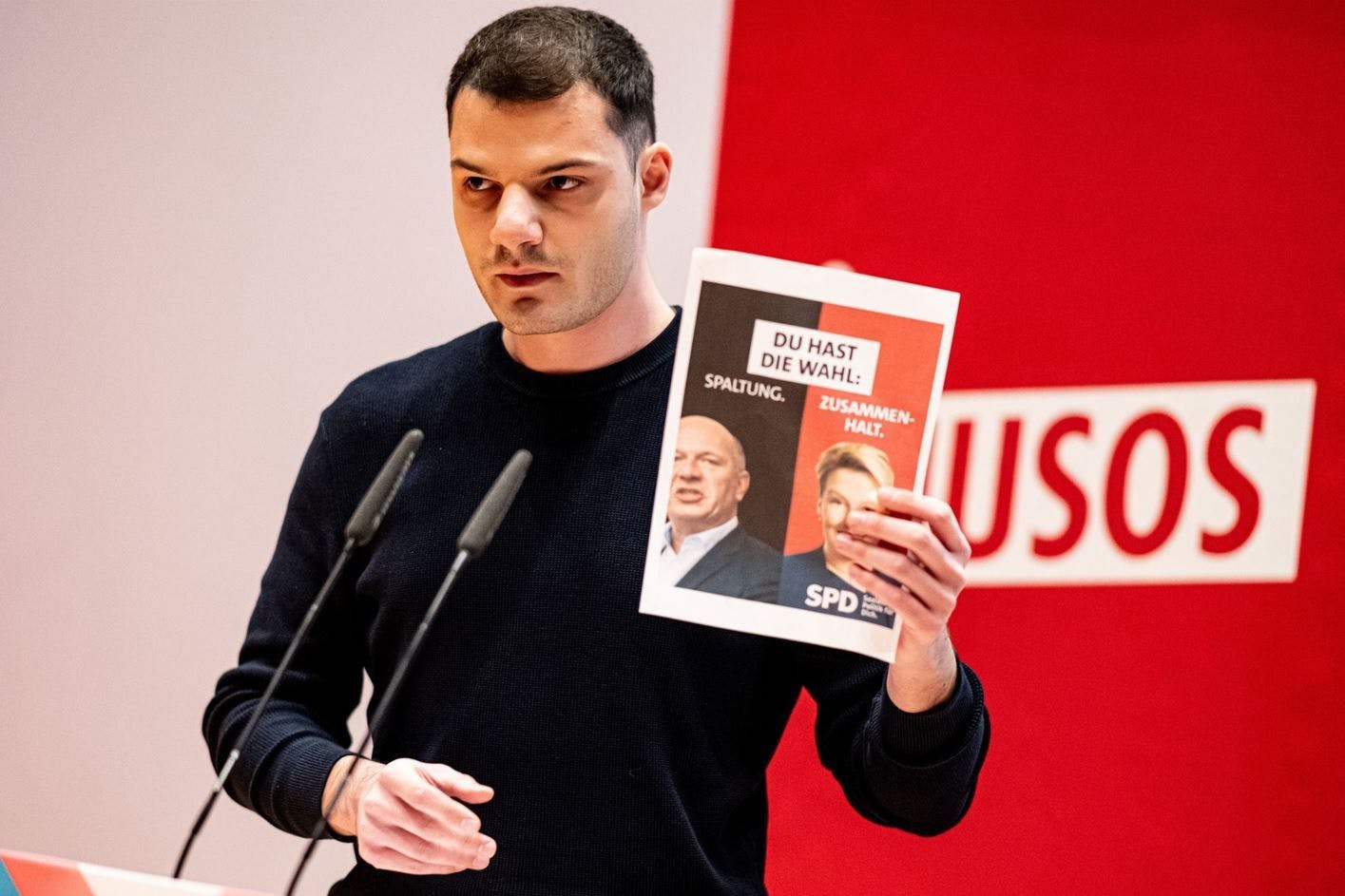 Kubilay Yalcin (SPD) hält auf der Landesdelegiertenkonferenz der Jusos Berlin ein Plakat mit Giffey und Wegner in die Höhe.