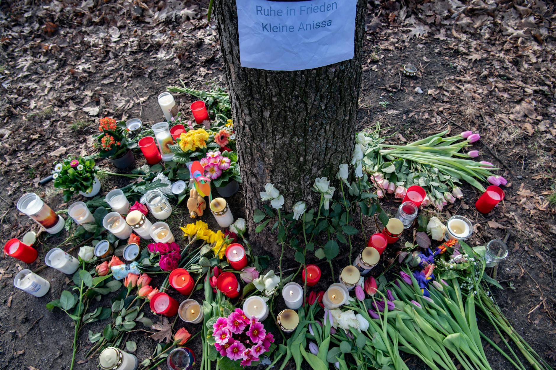 Unbekannte haben Blumen und Kerzen für Anissa an einem Baum im Bürgerpark Pankow abgelegt.