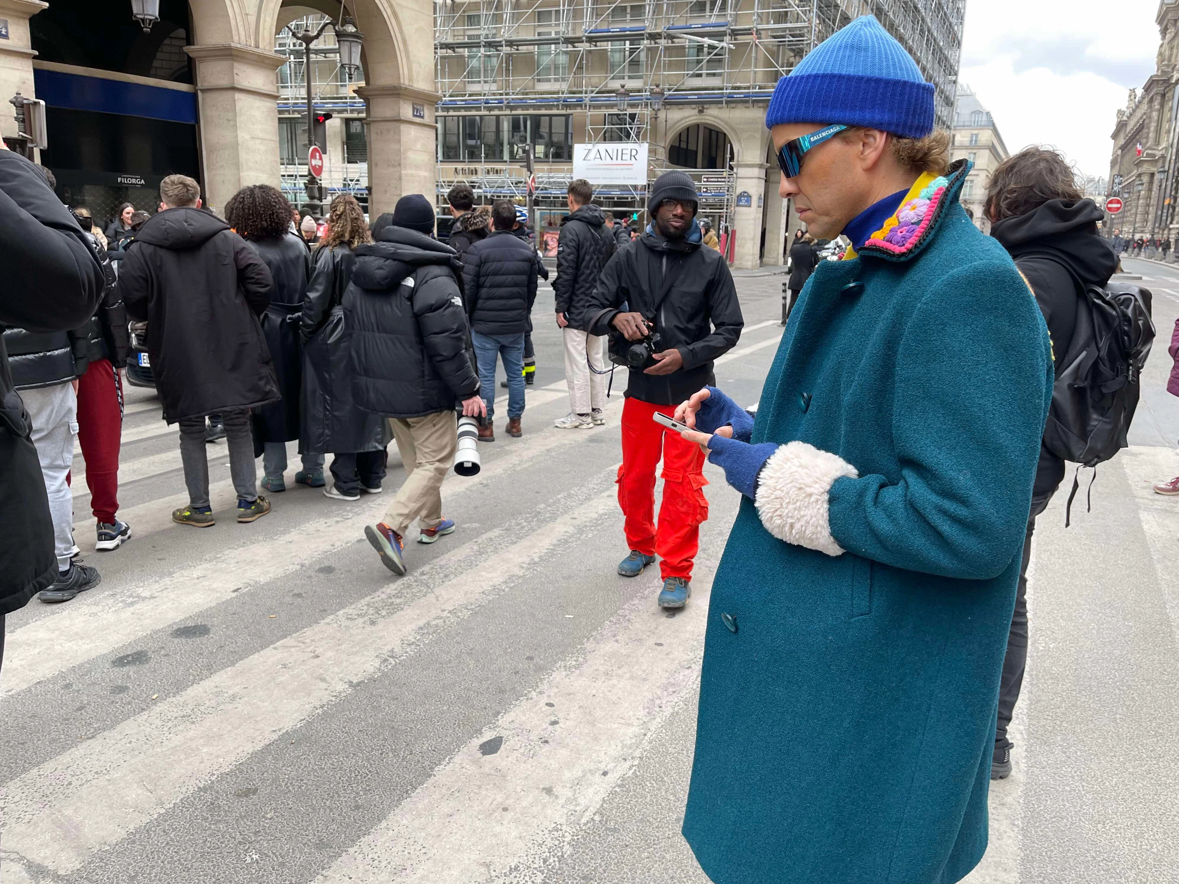 Mantel mit Häkelkragen und puschligen Ärmelschärpen: Der Spanier Ulisses de Melo ist Fashion-Enthusiast und glänzt vor den Fotografen gerne mit detailreichen Looks.