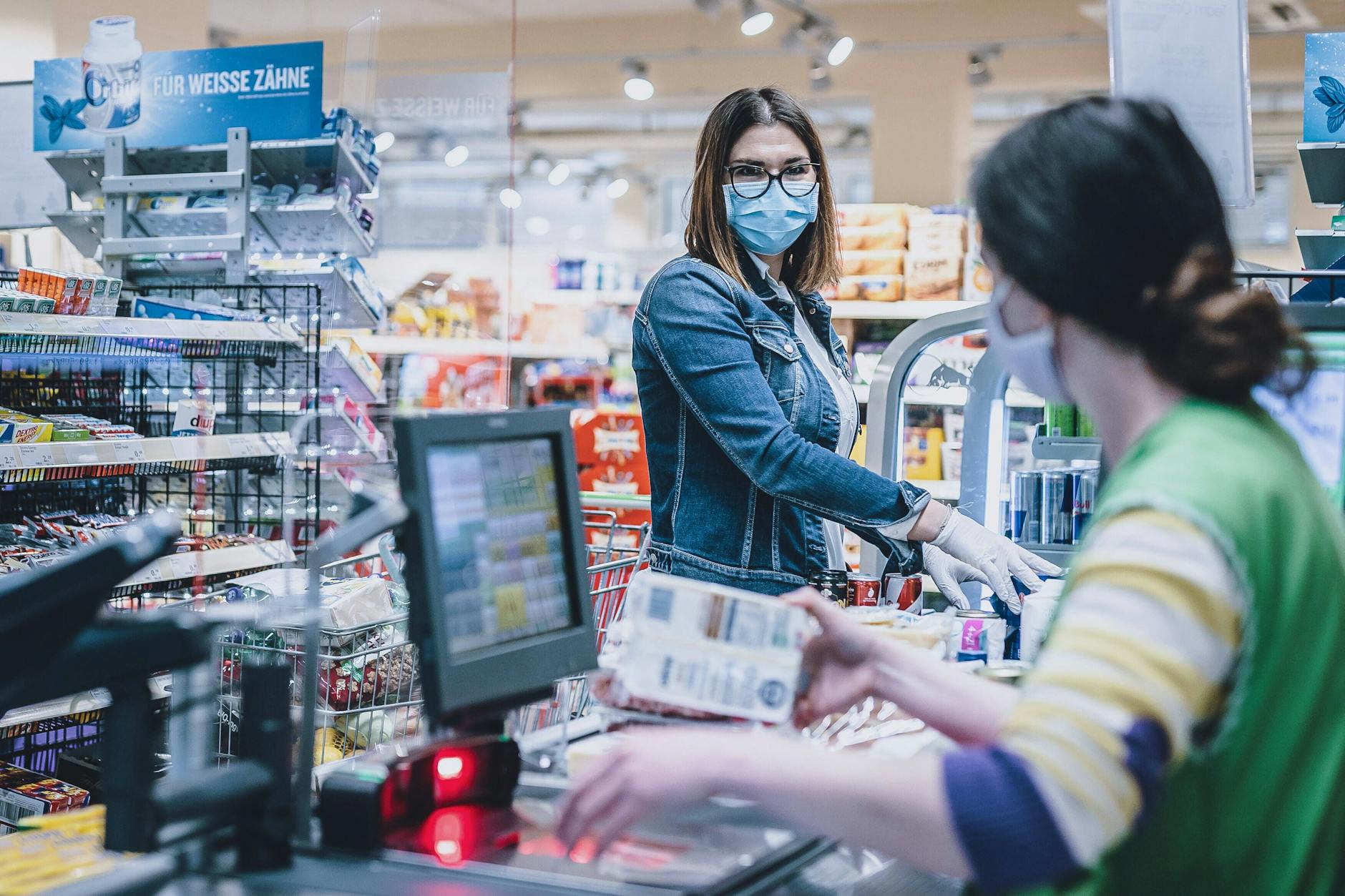 Eine Frau trägt eine Schutzmaske und Handschuhe bei ihrem Einkauf in einem Supermarkt.
