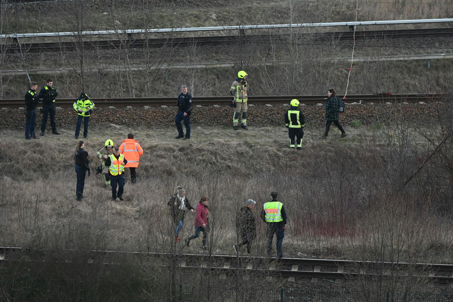 Einsatzkräfte untersuchen die Unfallstelle, nachdem ein Regionalzug mit einer herunterhängenden Oberleitung kollidiert ist.