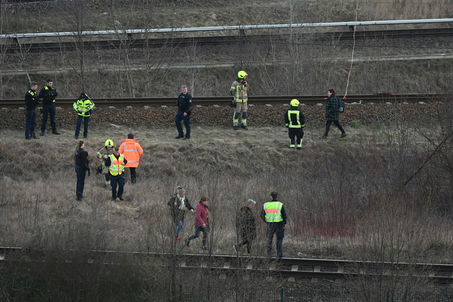 Einsatzkräfte untersuchen die Unfallstelle, nachdem ein Regionalzug mit einer herunterhängenden Oberleitung kollidiert ist.