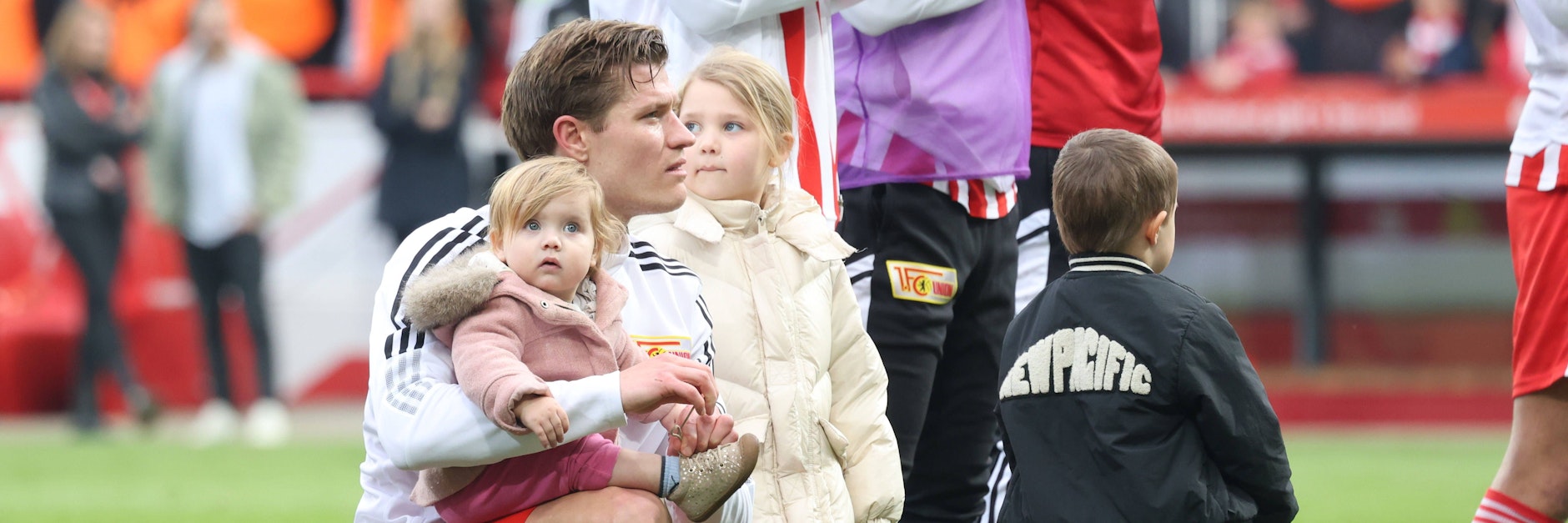 Kevin Behrens feiert den Sieg des 1. FC Union zusammen mit seine Töchtern auf dem Rasen der Alten Försterei.