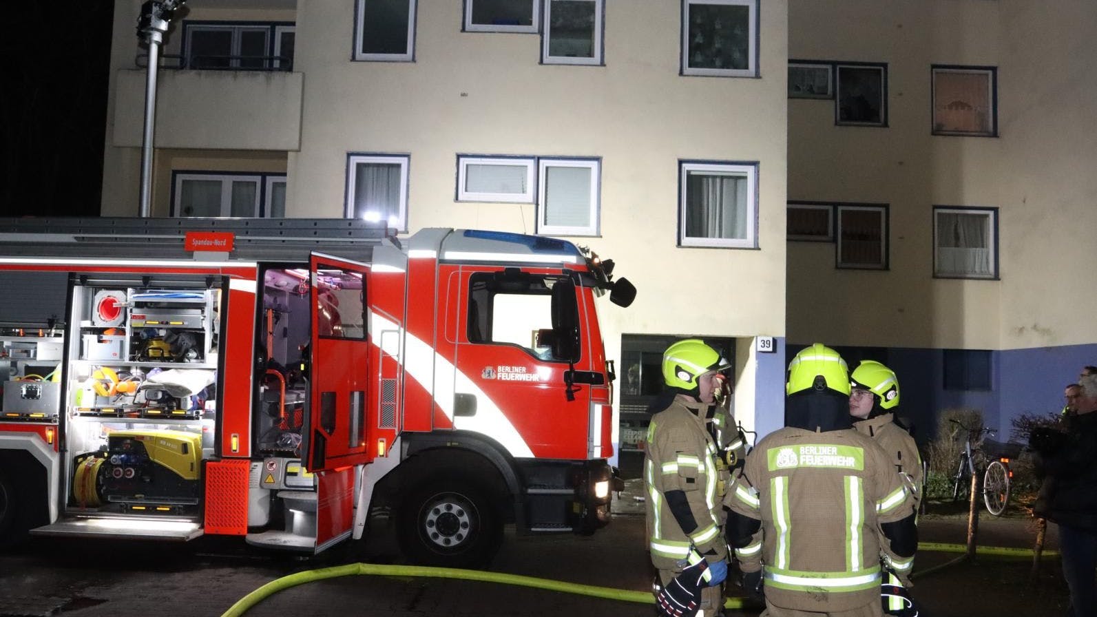 Einsatzkräfte stehen vor dem Brandhaus.