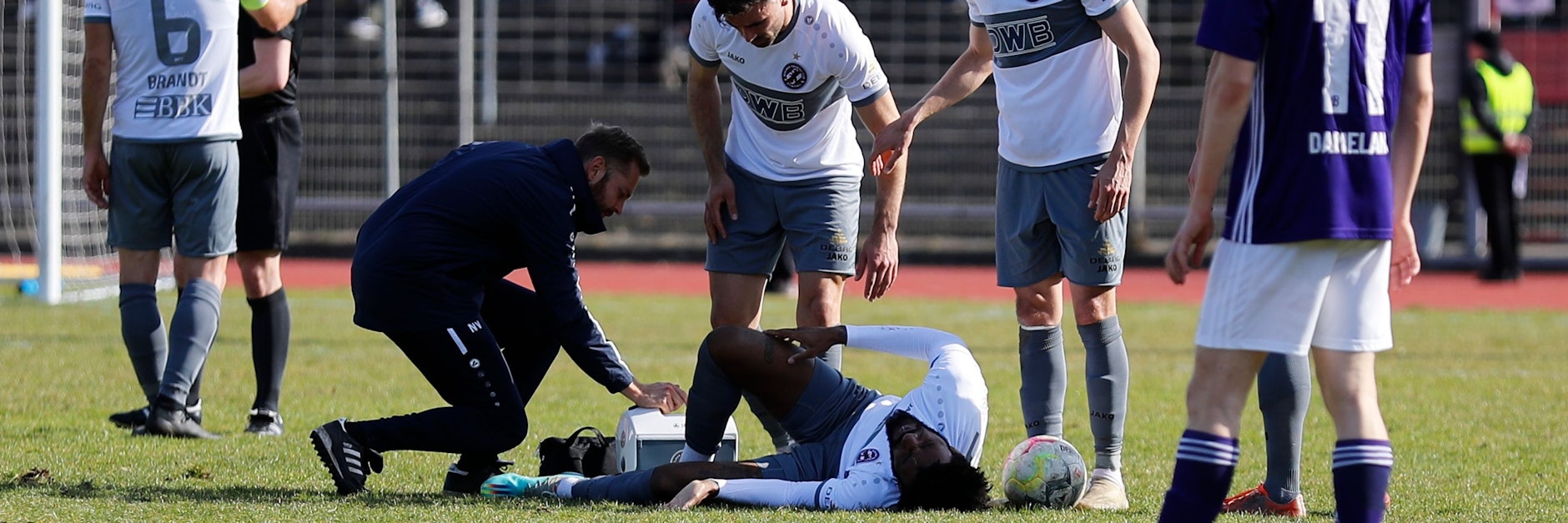 BFC-Hüne Dominic Duncan krümmt sich vor Schmerzen, seine Dynamo-Kollegen betrachten das mit Sorge.