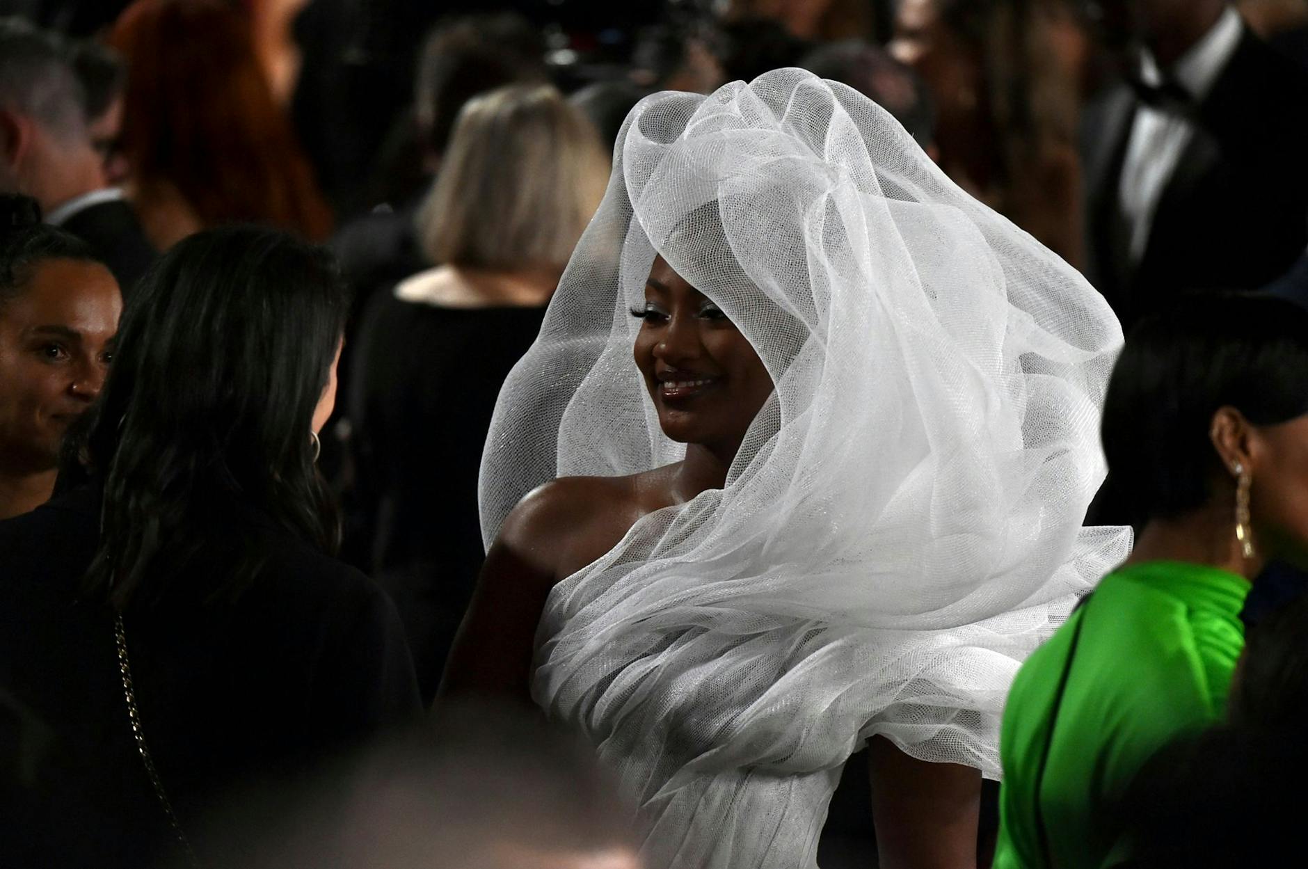 Sie fällt auf: Sängerin Tems kommt in einem aufregenden weißen Outfit zur Oscar-Verleihung. Weniger Glück hatten allerdings die Gäste, die im Saal hinter ihr saßen.