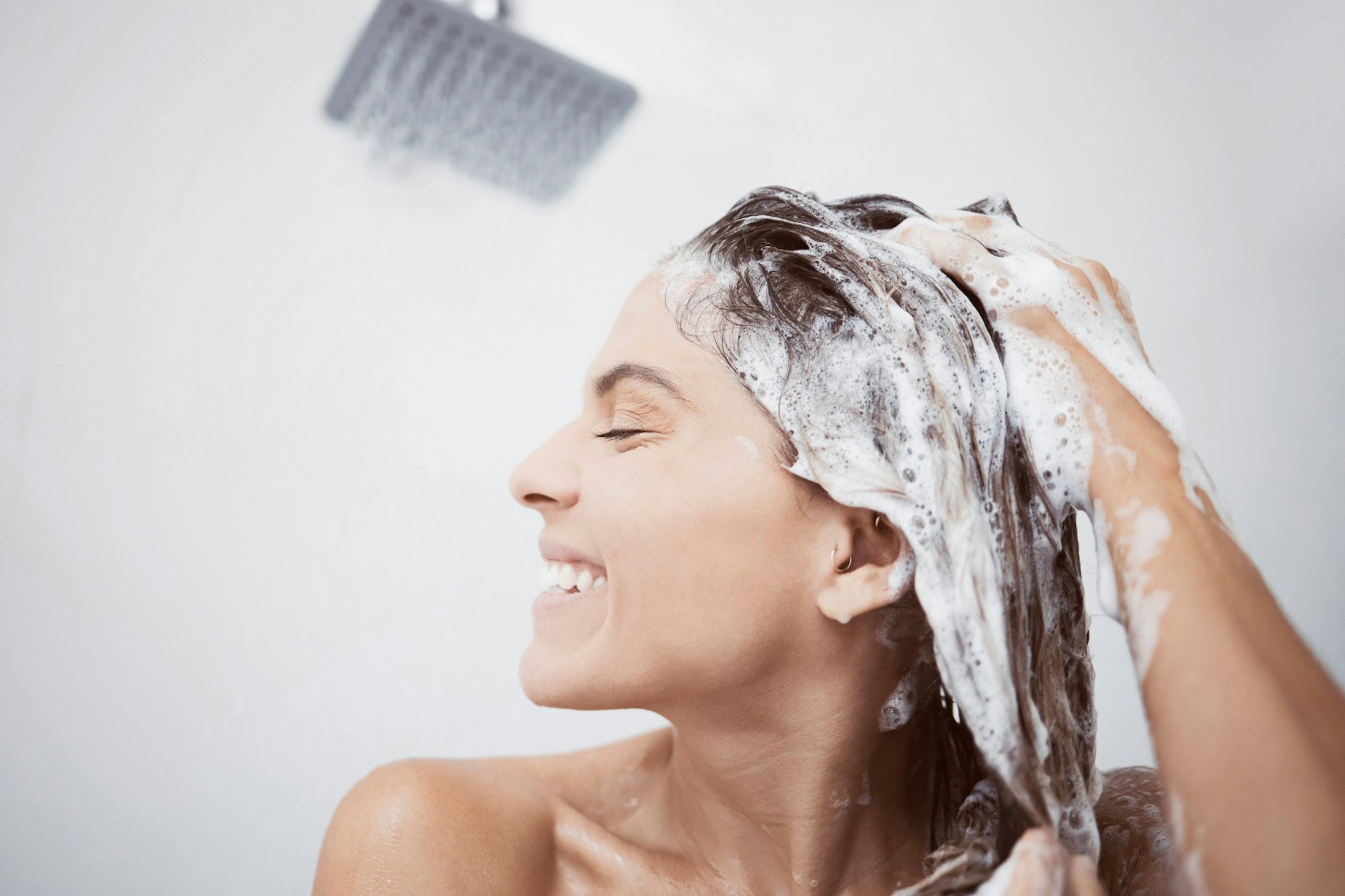 Eine Frau wäscht sich unter der Dusche die Haare.