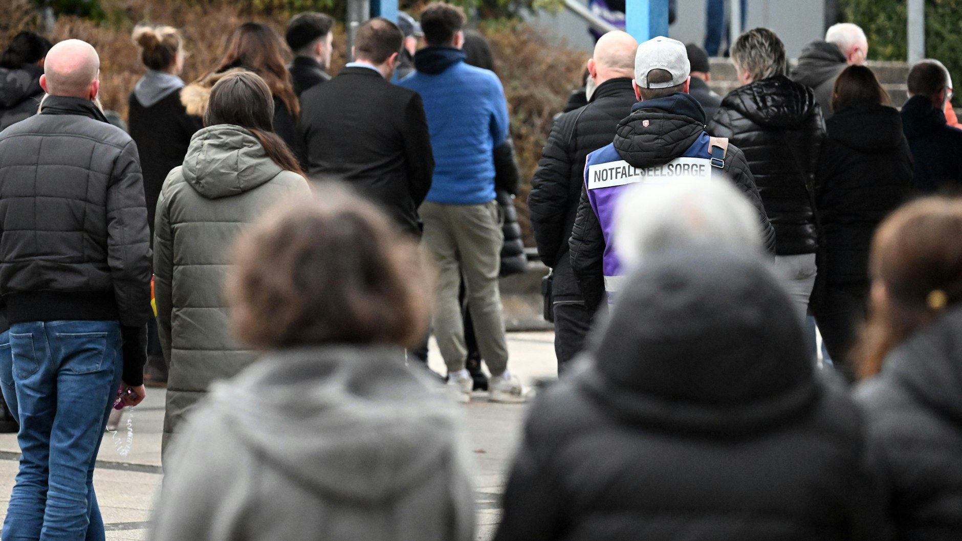 Zahlreiche Menschen verfolgen auf dem Hof der Gesamtschule die Trauerfeier, die aus der Kirche übertragen wird.