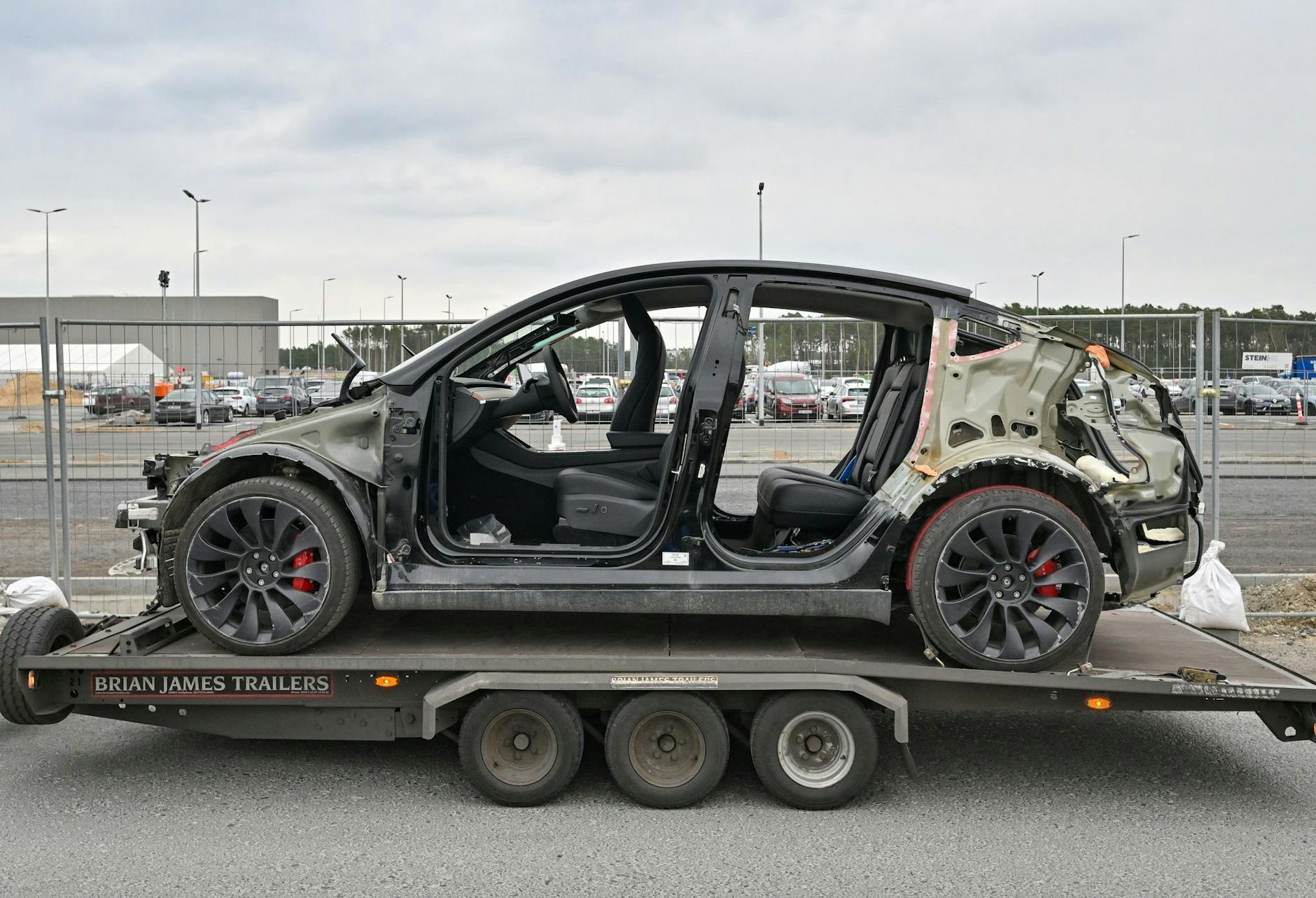 ARCHIV - Ein defektes Elektrofahrzeug vom Typ Model Y steht auf einem Anhänger vor dem Werk der Tesla Gigafactory Berlin Brandenburg.