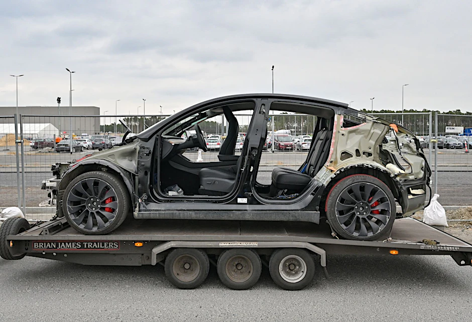 ARCHIV - Ein defektes Elektrofahrzeug vom Typ Model Y steht auf einem Anhänger vor dem Werk der Tesla Gigafactory Berlin Brandenburg.  