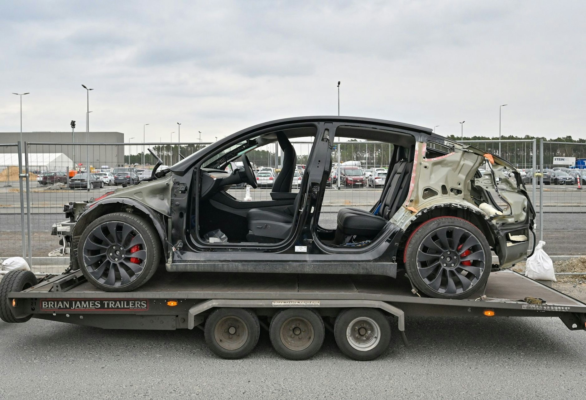 ARCHIV - Ein defektes Elektrofahrzeug vom Typ Model Y steht auf einem Anhänger vor dem Werk der Tesla Gigafactory Berlin Brandenburg.  