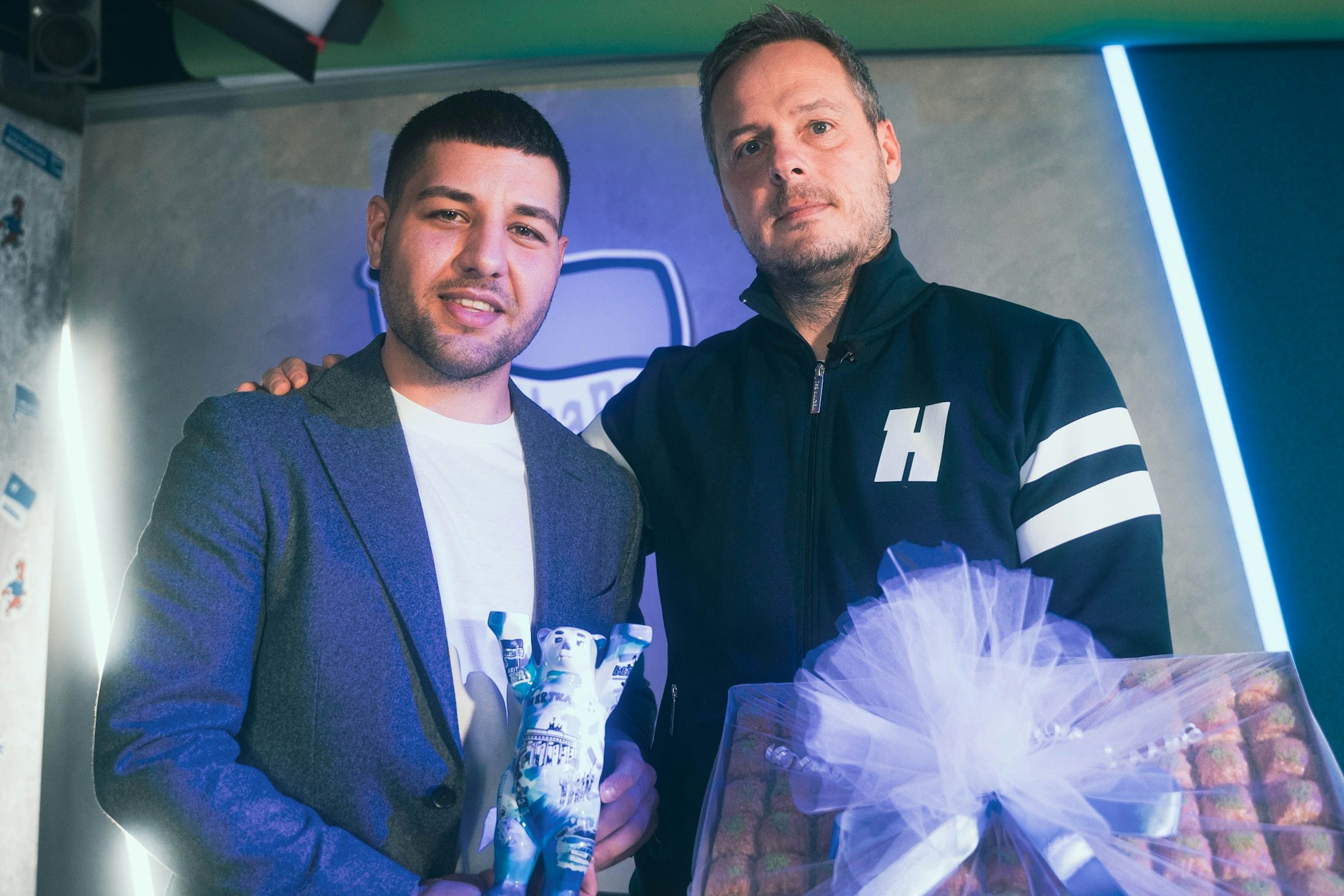 BAK-Präsident Ebubekir Han (l.) und Hertha-Präsident Kay Bernstein mit Buddy-Bär und Baklava bei der Verabredung zum Benefizspiel.