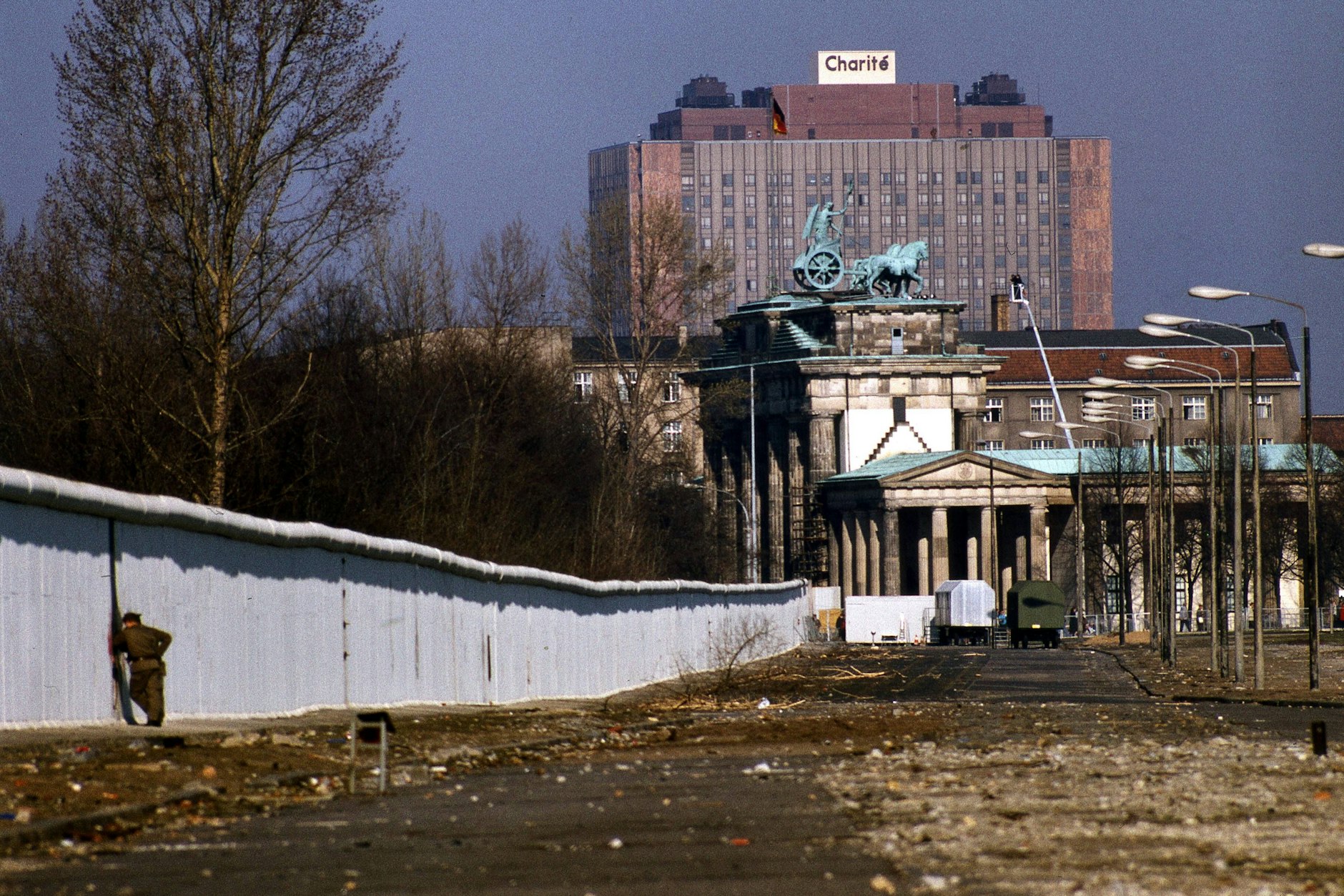 1990: die gefallene Berliner Mauer nahe dem Brandenburger Tor, das Charité-Hochhaus im Hintergrund