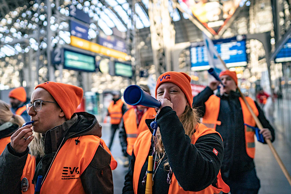 Streikende der Eisenbahn- und Verkehrsgewerkschaft EVG ziehen durch einen Bahnhof.