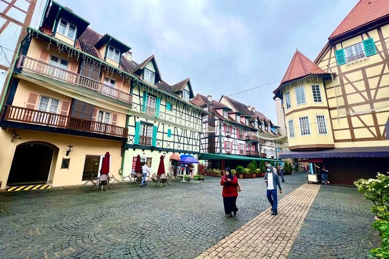 Besucher schlendern über das Kopfsteinpflaster durch Colmar Tropicale, vorbei an Fachwerkhäusern mit Türmchen, Erkern und bunten Fensterläden.