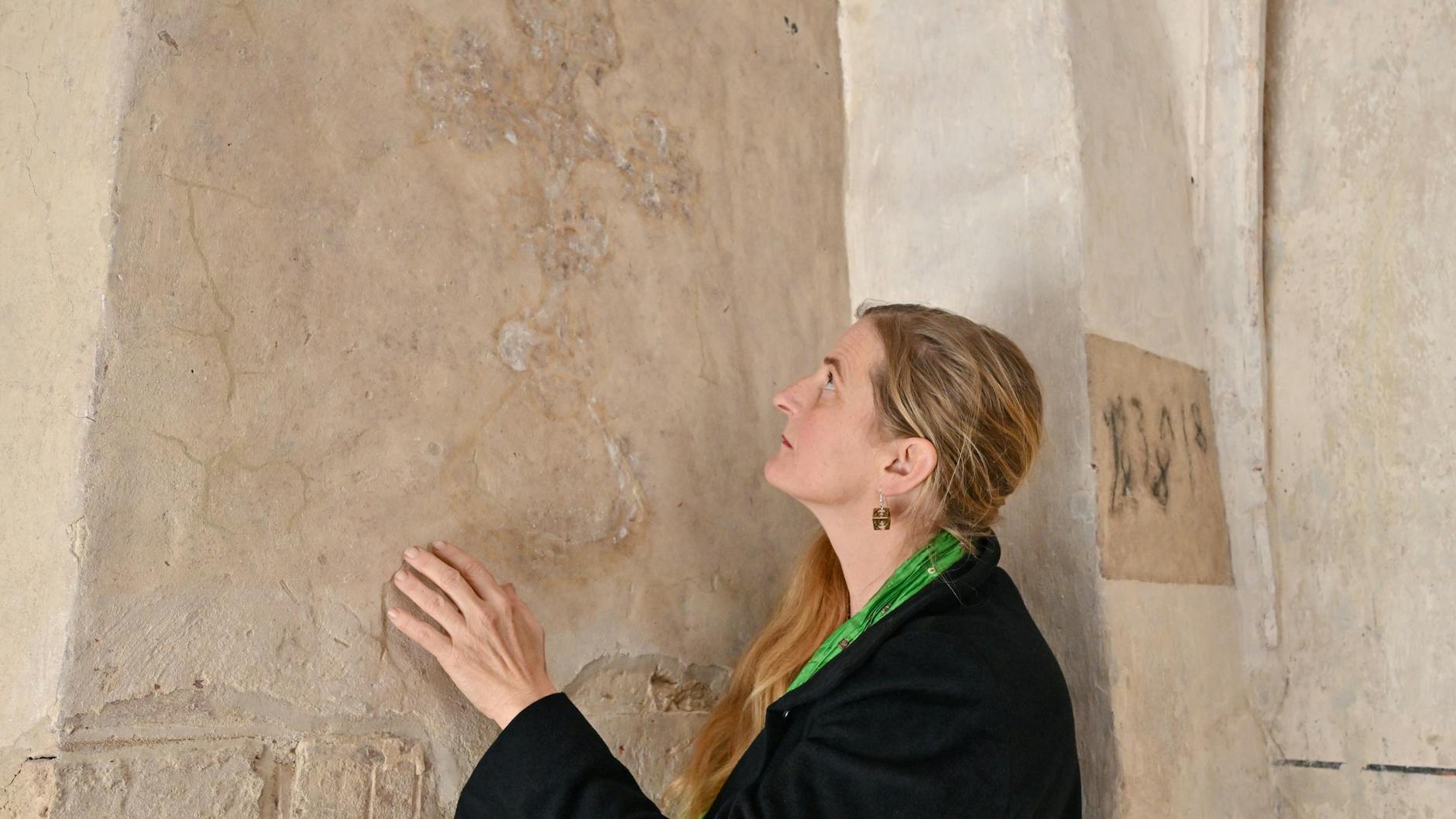 Restauratorin Dorothee Schmidt-Breitung vor den schemenhaften Überresten einer historischen Wandmalerei im Kloster Neuzelle