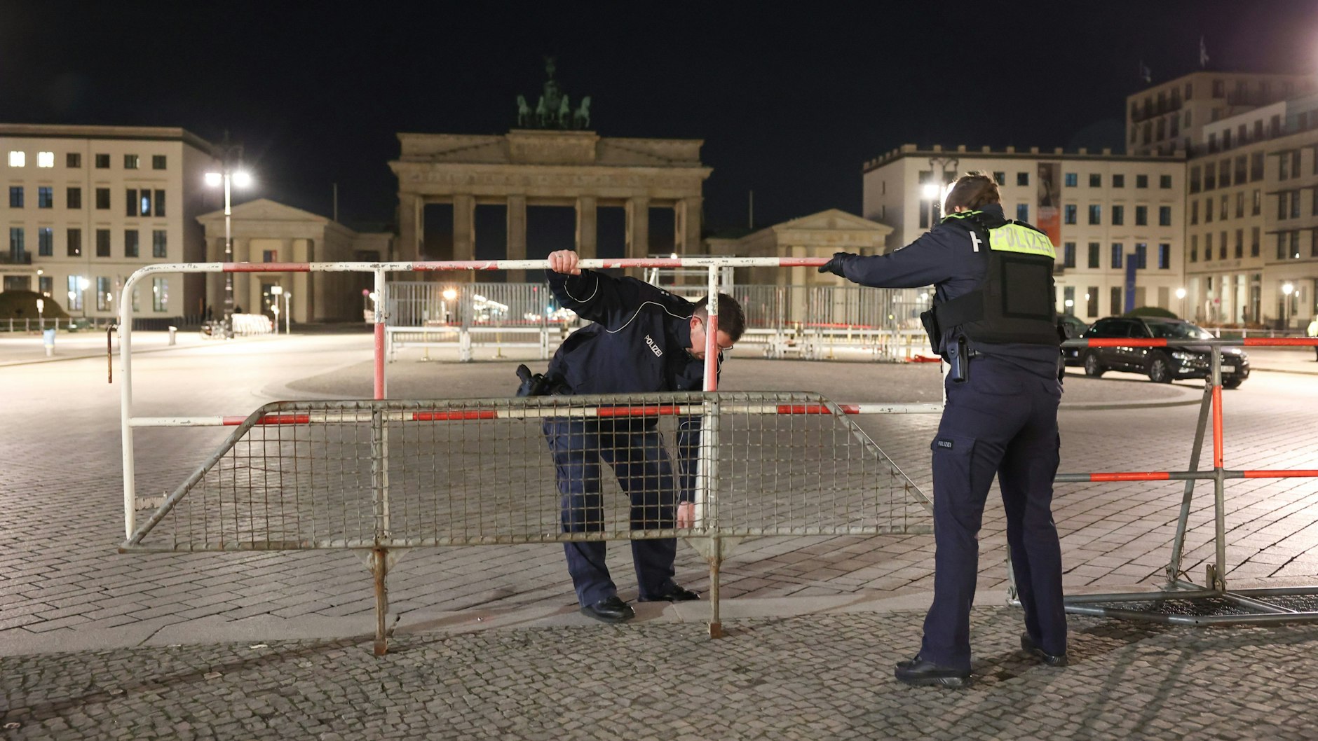 Einsatzkräfte der Polizei bauen für den Berlin-Besuch von König Charles III. einen Zaun auf dem Pariser Platz vor dem Brandenburger Tor auf.&nbsp;